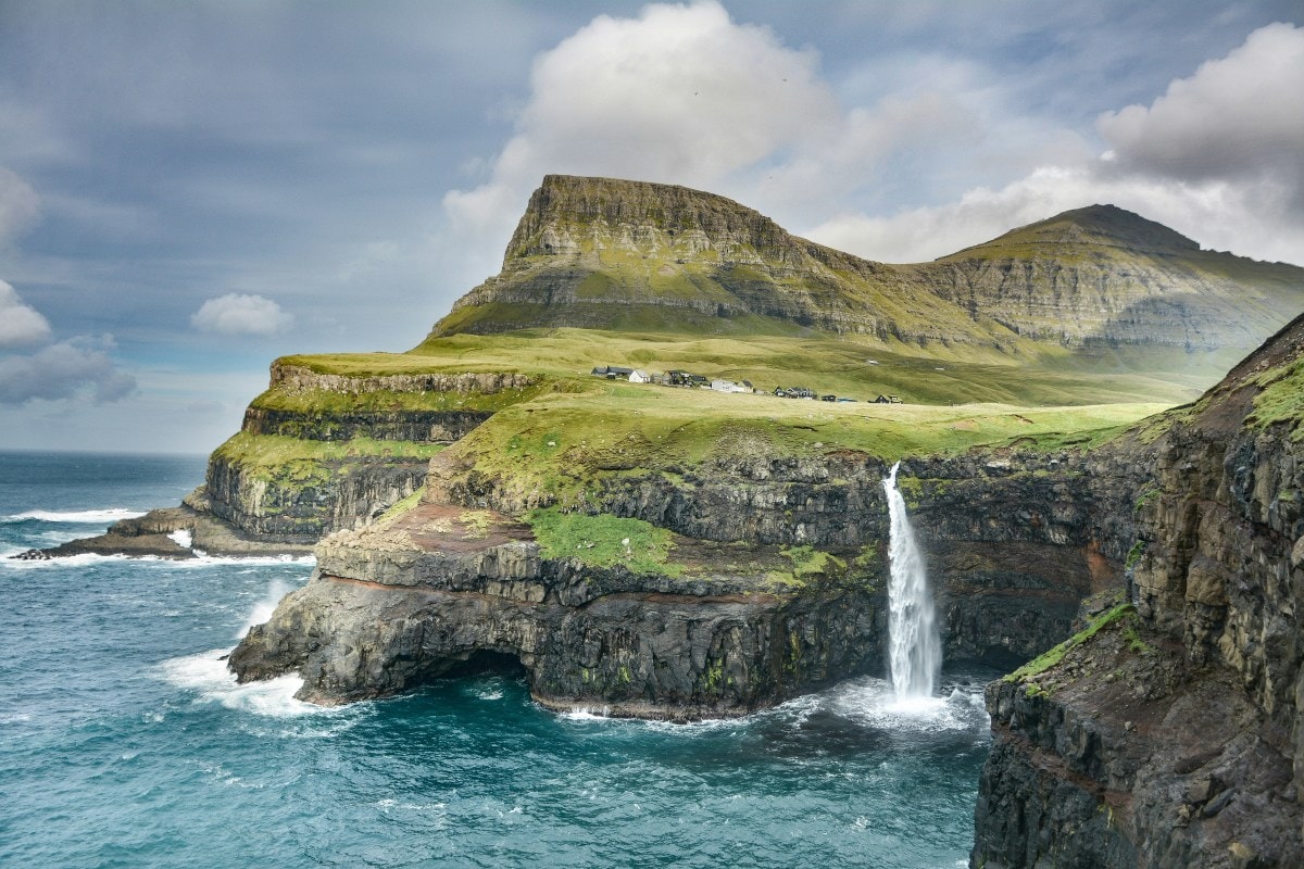 Waterfalls on a mountain going into the ocean during the daytime
