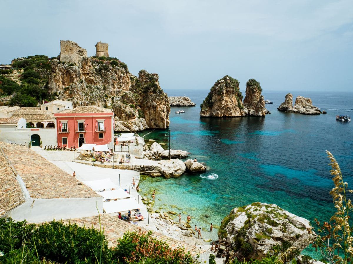 a pink villa sits on the shores of a turquoise lagoon