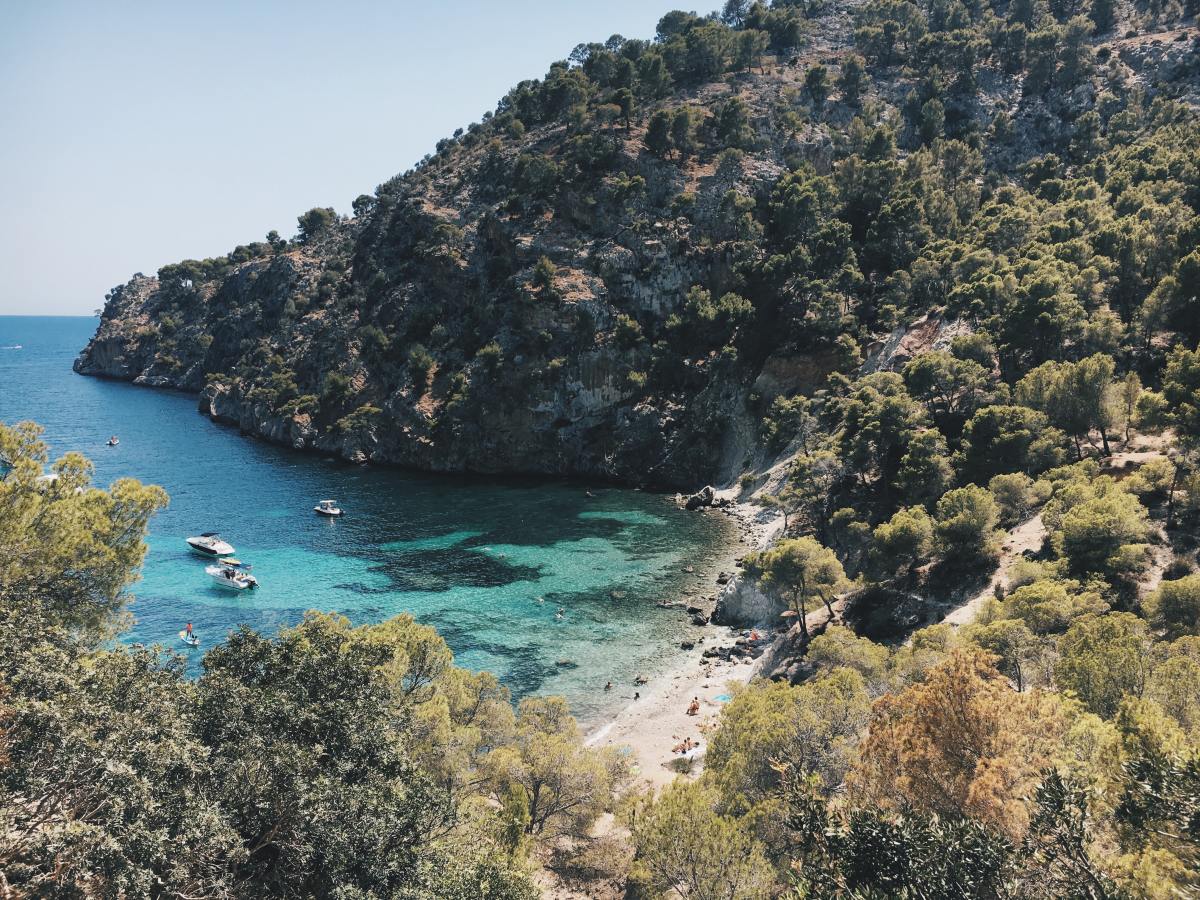 Serene turquoise waters in Mallorca, Spain beside cliffs and modern houses alongside.