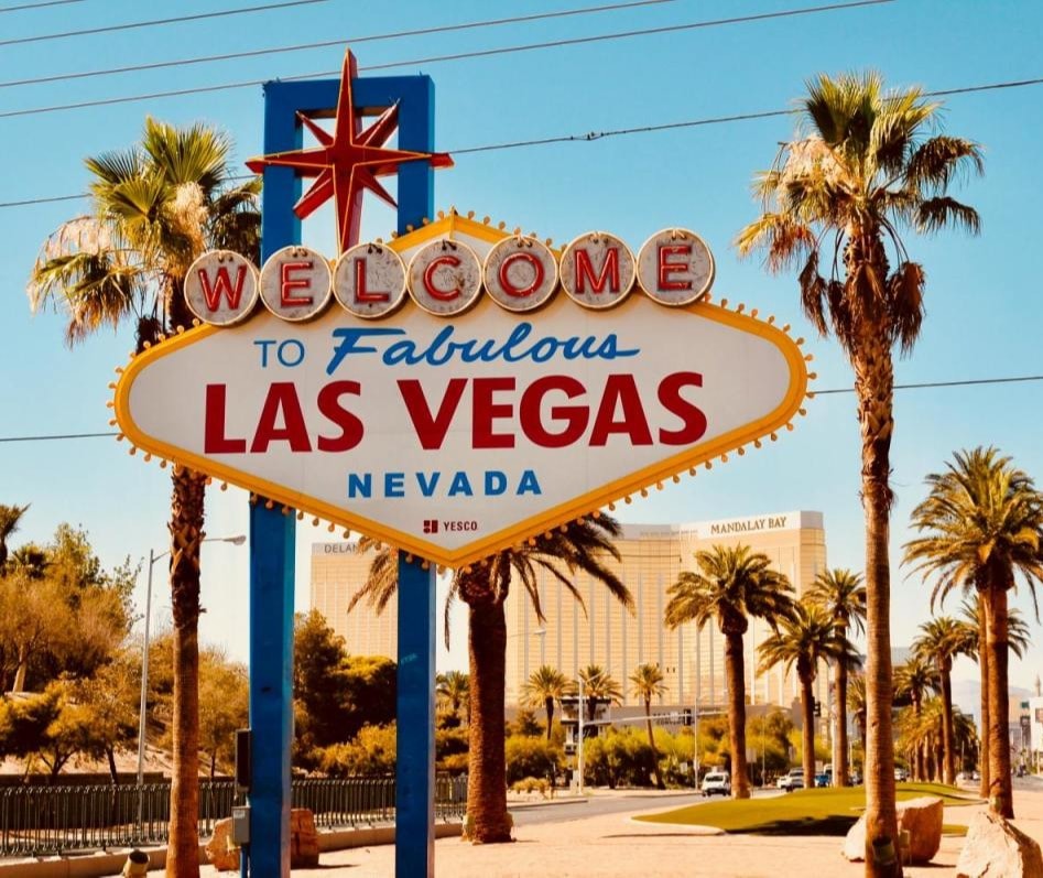 Iconic entrance sign to Las Vegas at the front of city border with palm trees in the background.