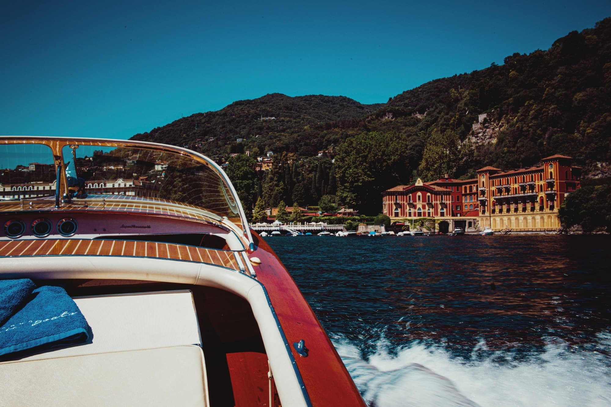 red boat cruising on the sea in front of a red villa