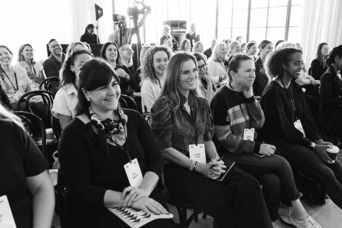a group of people sitting in chairs in an audience smile