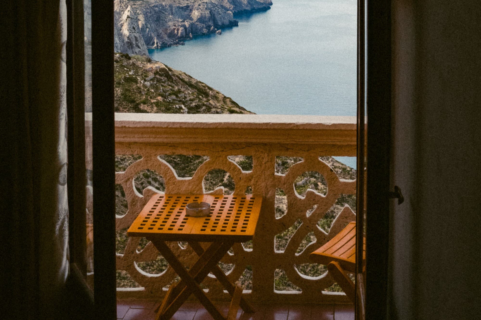 a small table and a chair on a balcony over looking the sea