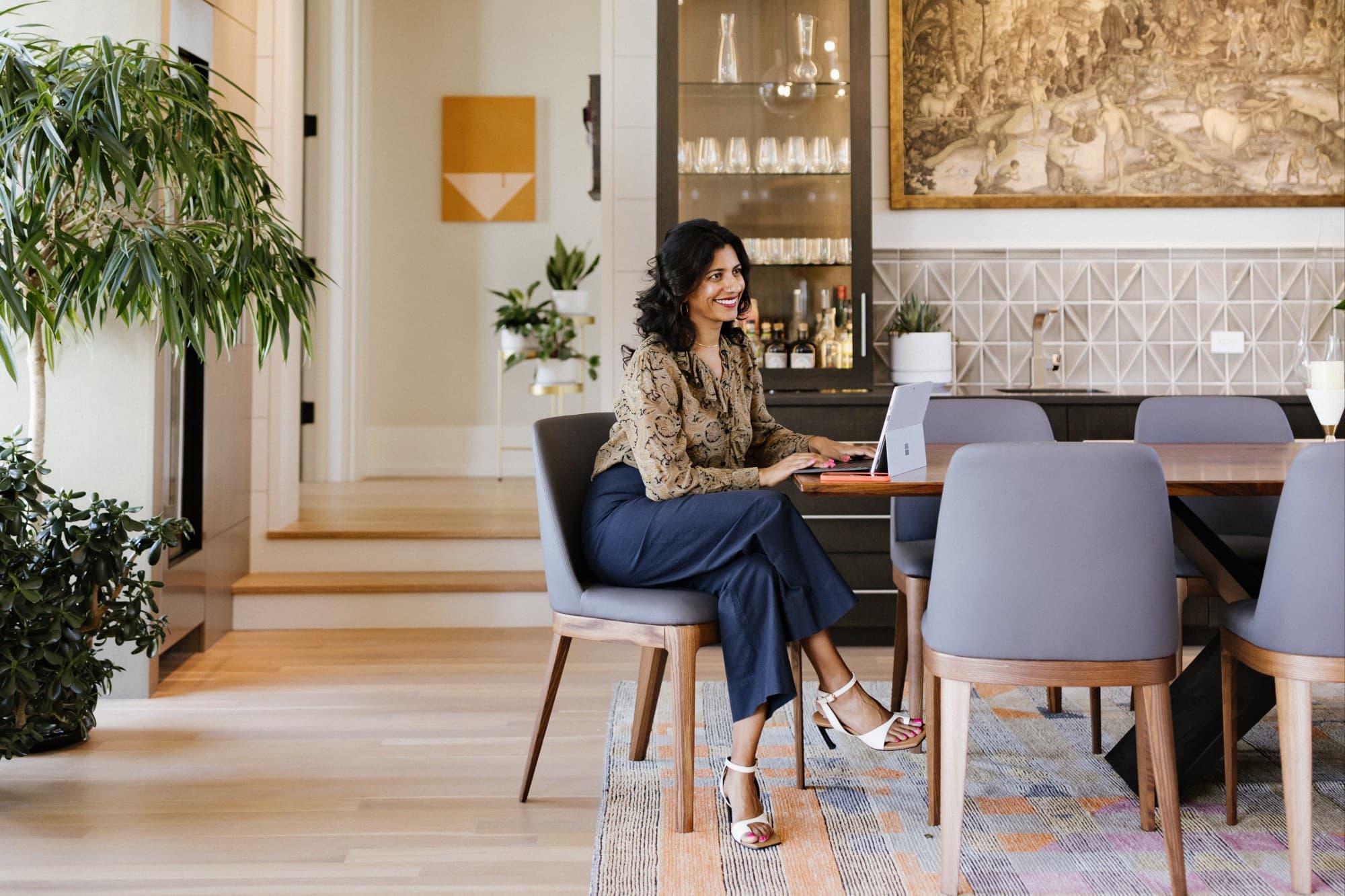 advisor Gaya Vinay sitting at a kitchen table with her laptop