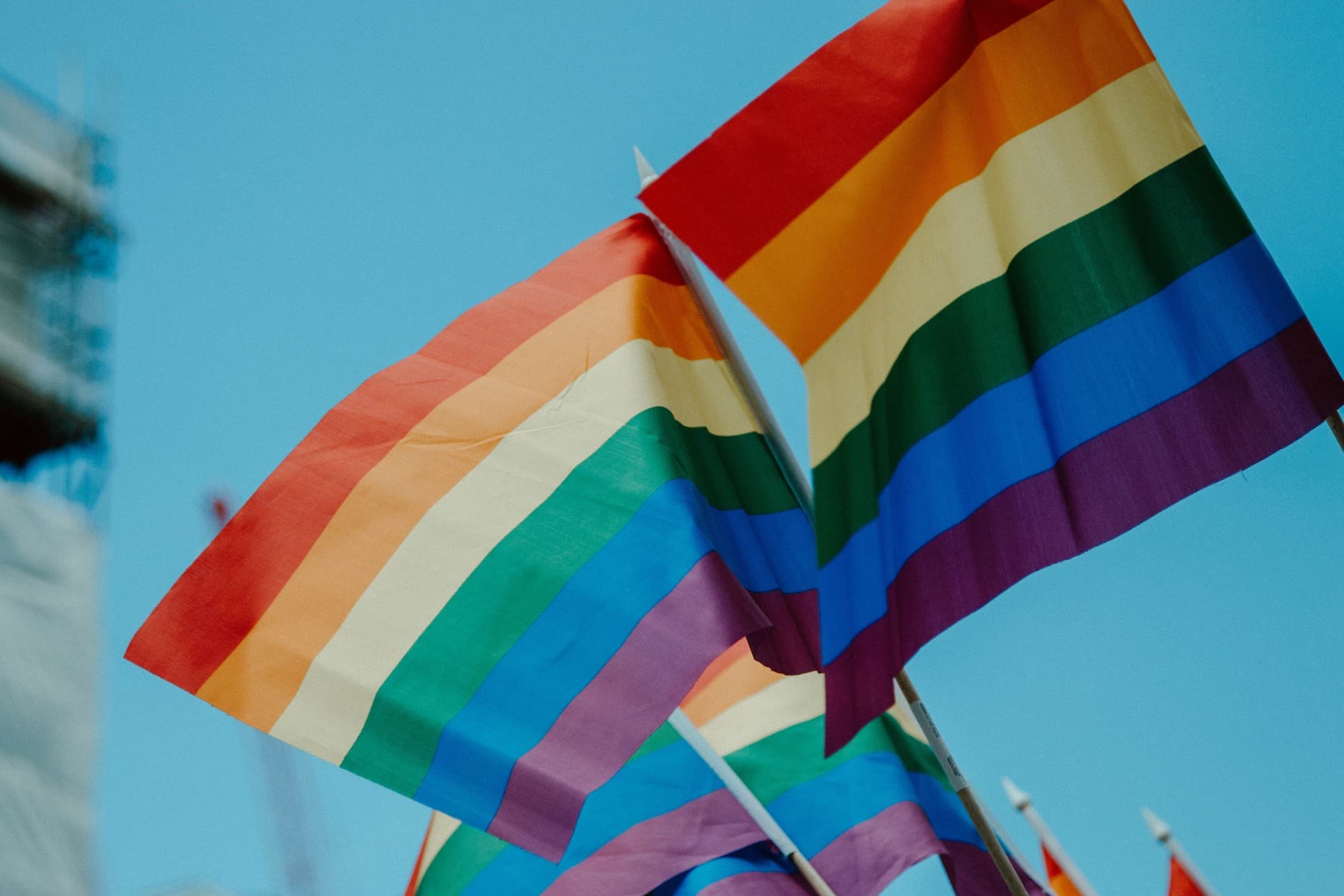 rainbow flag waving against a blue sky