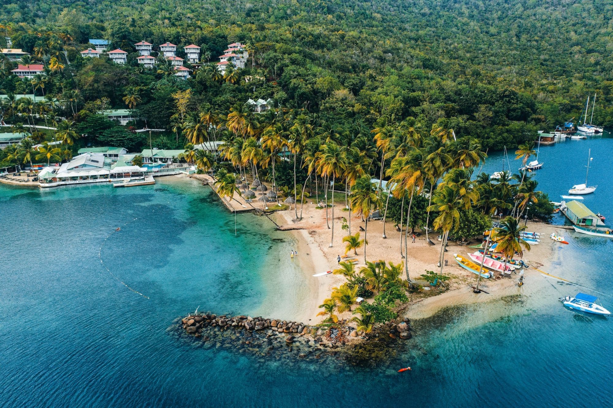 Incredibly clear-blue waters surround a tiny peninsula made up of palm trees, white-sand beaches and small rock walls. Canoes line the shore and small homes dot the hills (photo by Omar Eagle-Clarke)