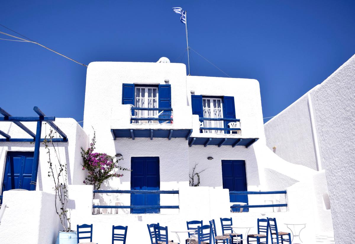 Pristine white and blue cement houses in Mykonos, Greece against blue sky.