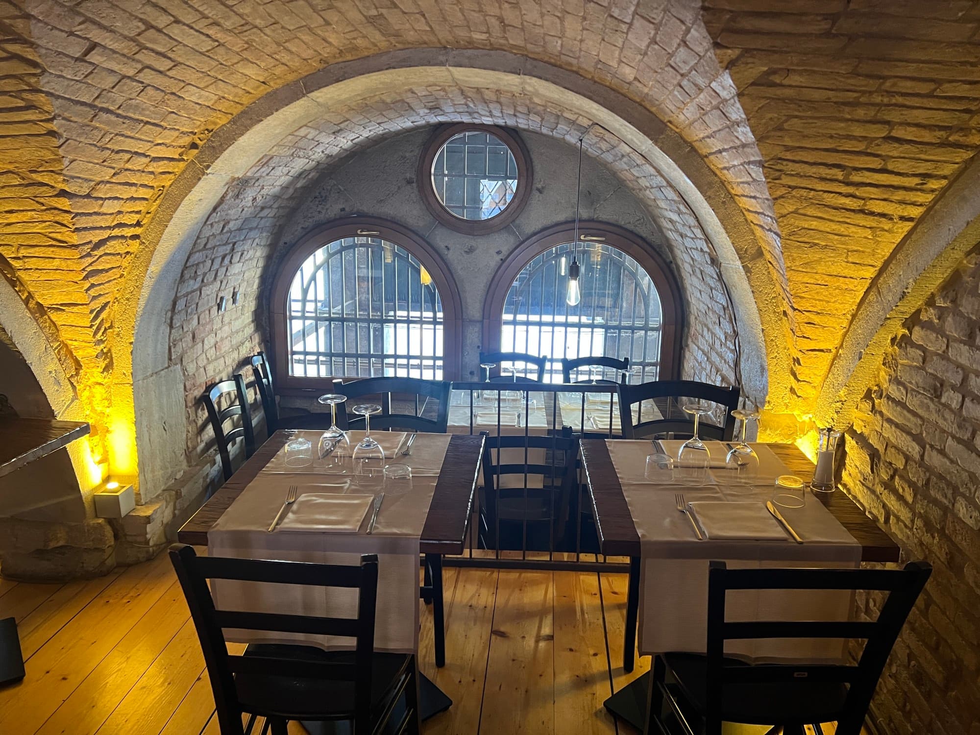 A dining area in a dimly lit room with arched windows
