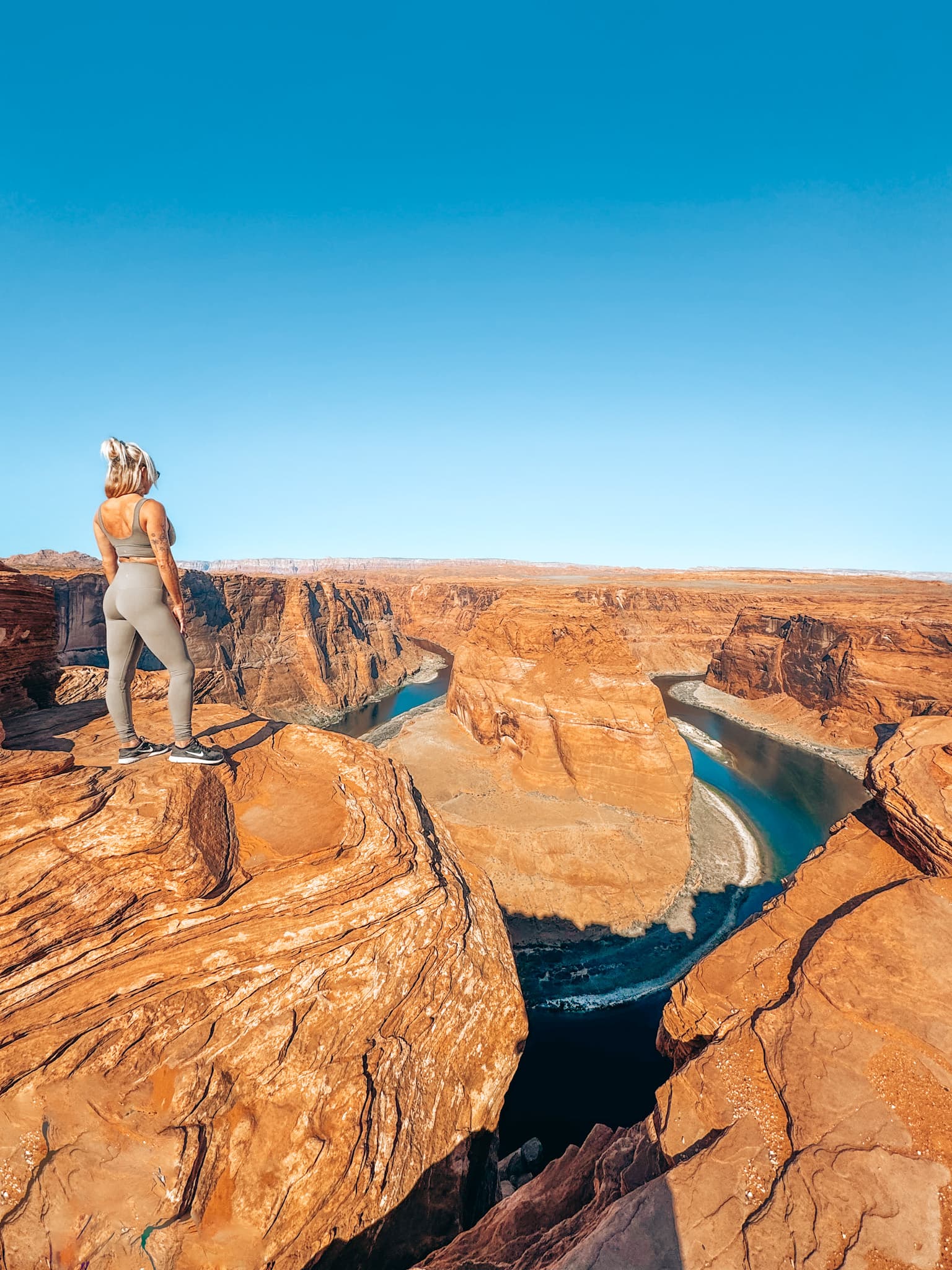 Travel advisor posing at the top of red mountains look out on a valley during the daytime