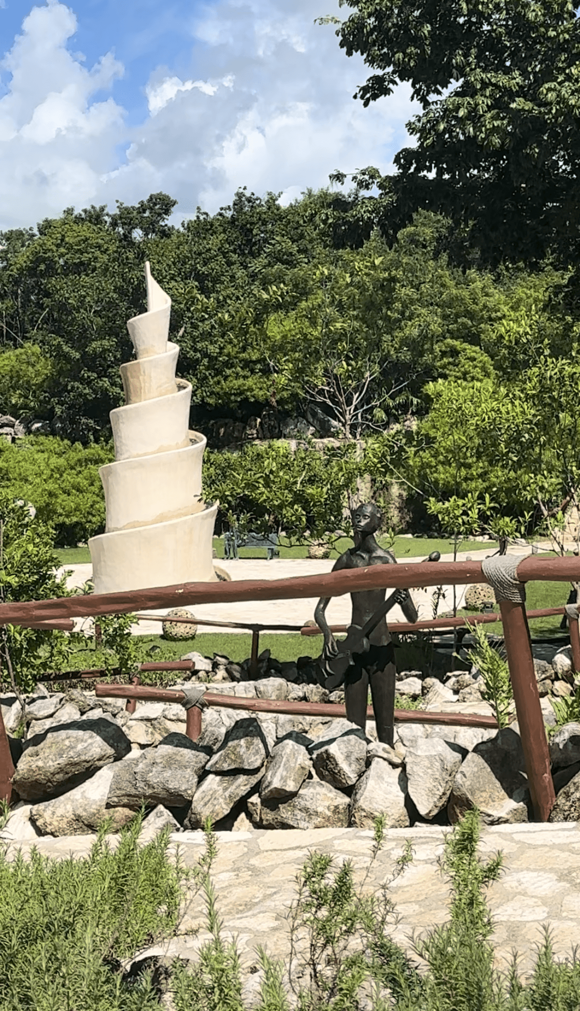 An outside park area with a spiral structure in the center, surrounded by a forest