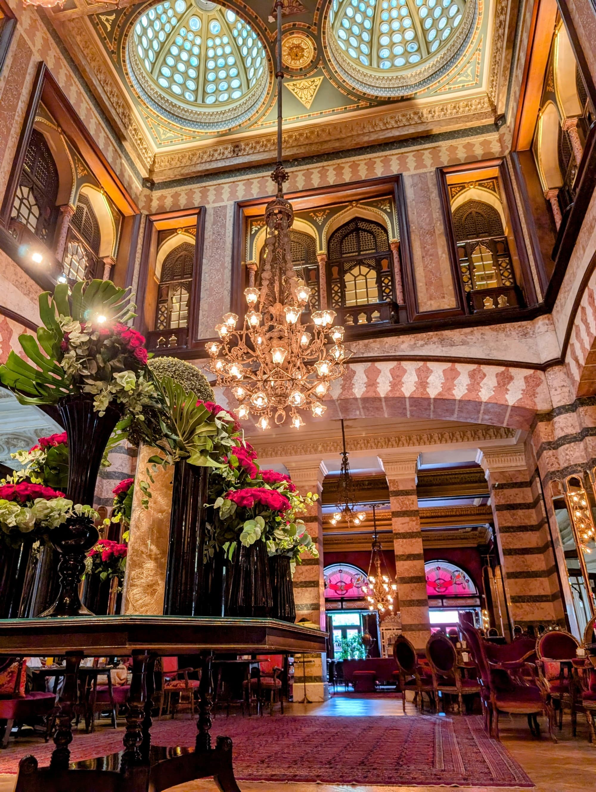 Interior of a luxurious hotel lobby with glass skylights and an Art Deco chandelier.