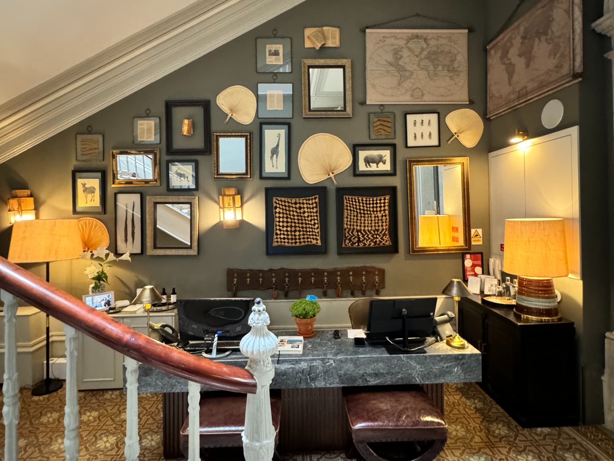 A reception desk of a hotel against a wall with multiple pieces of artwork