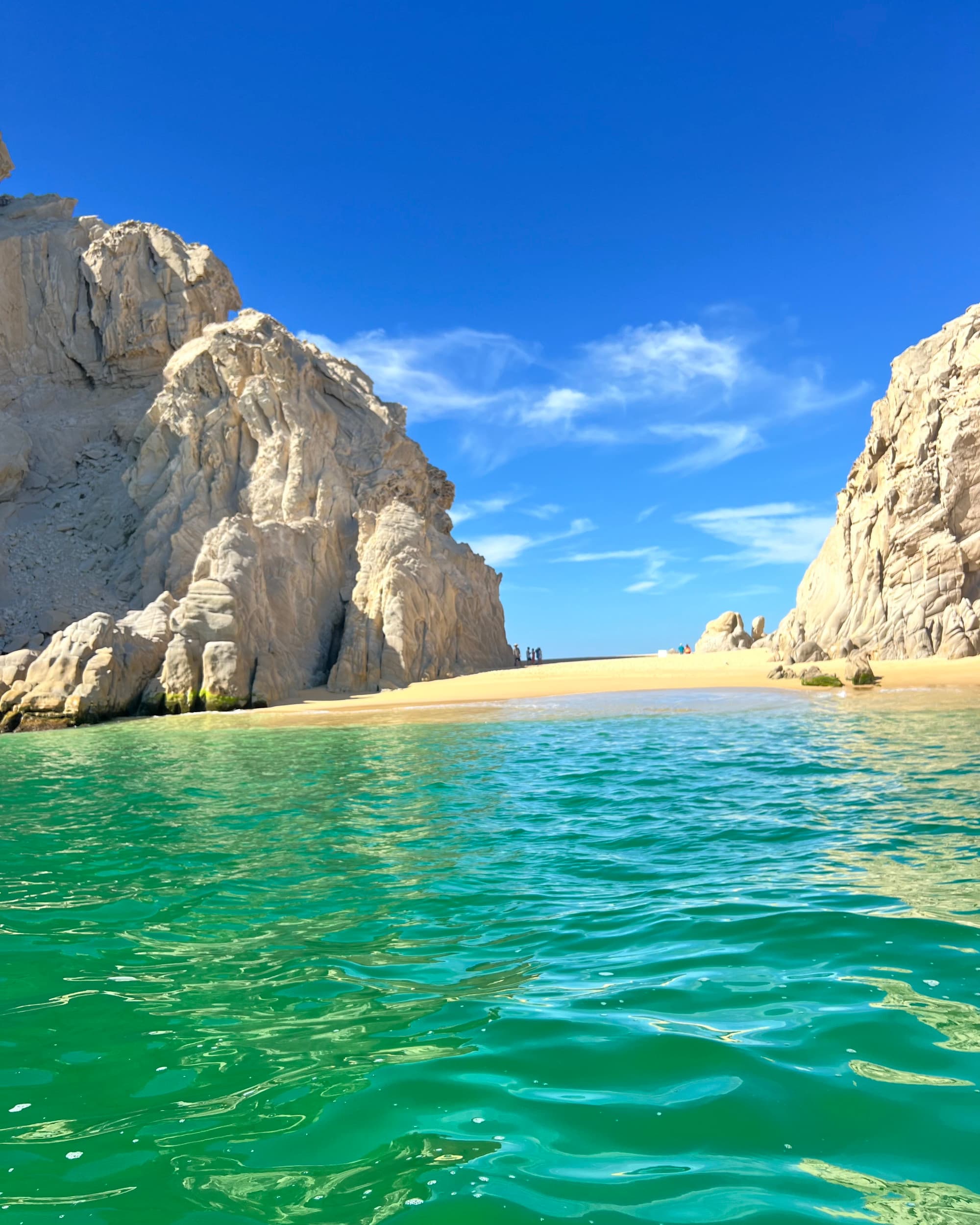 Green water leading to sand between two rocky outcroppings at Lovers Beach Los Cabos.