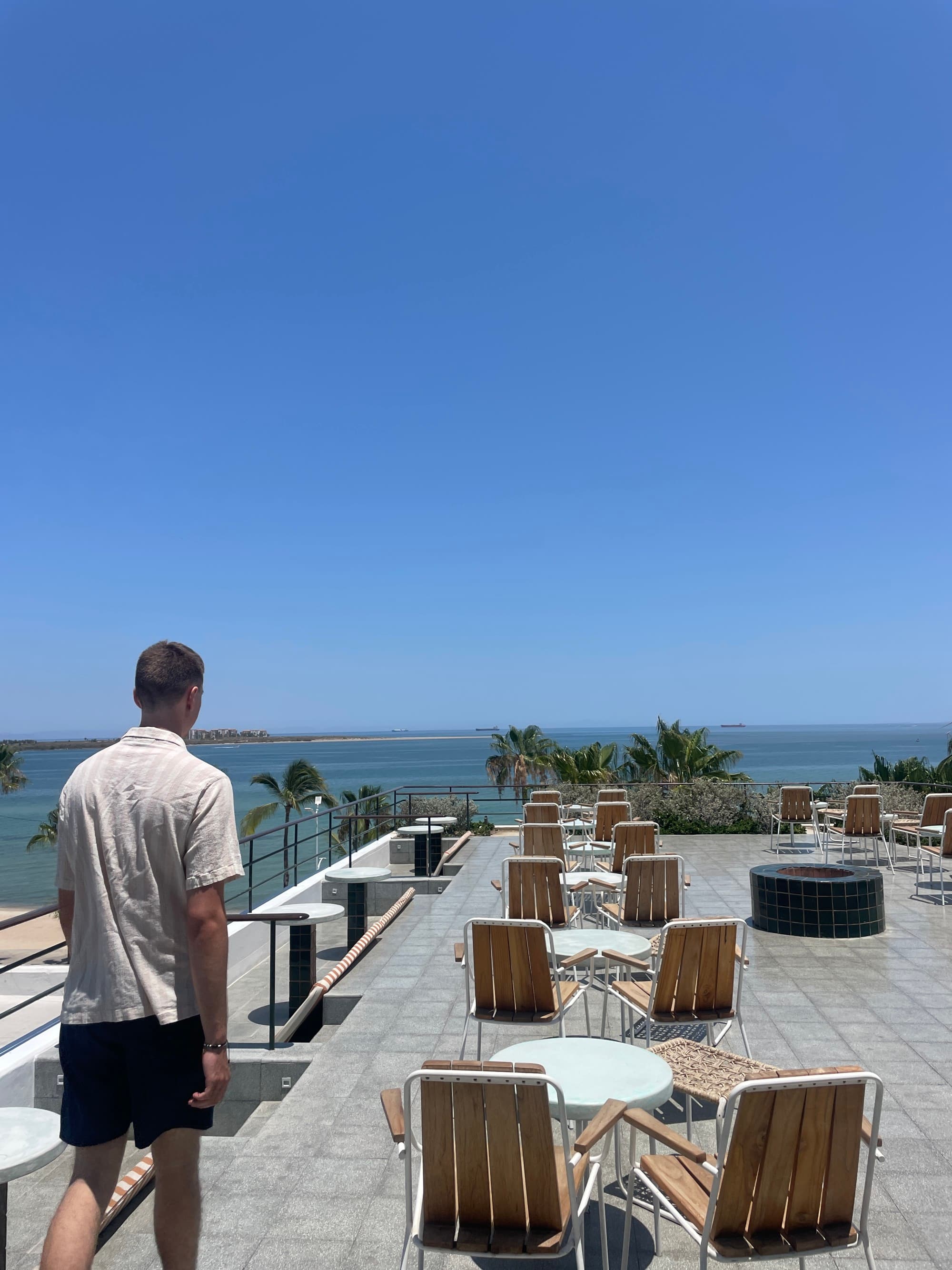 Seaside dining area with wooden chairs and an ocean view in the back.
