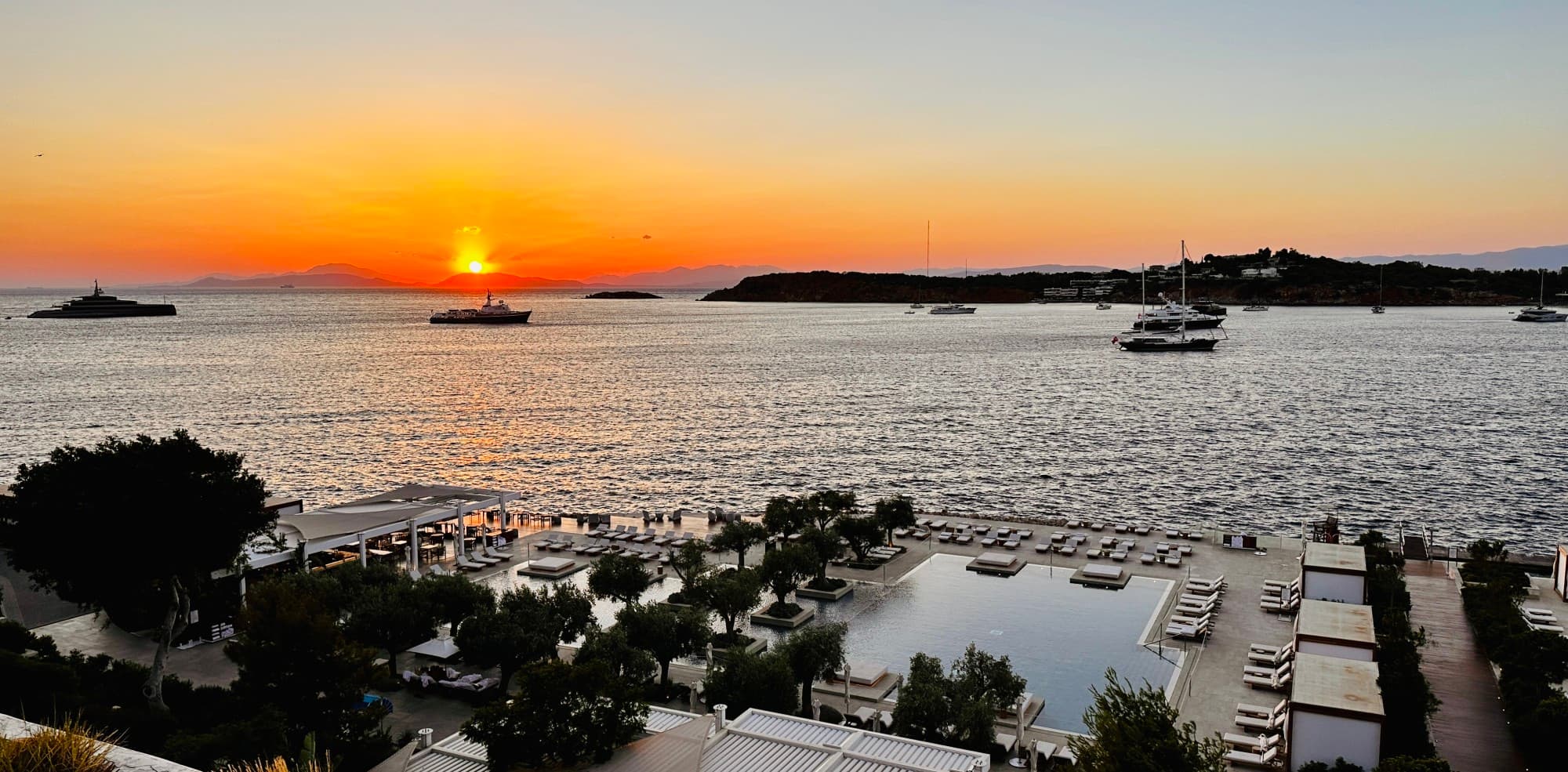 Sunset view from the hotel at seaside, Athens as the sun dips below the ocean horizon.