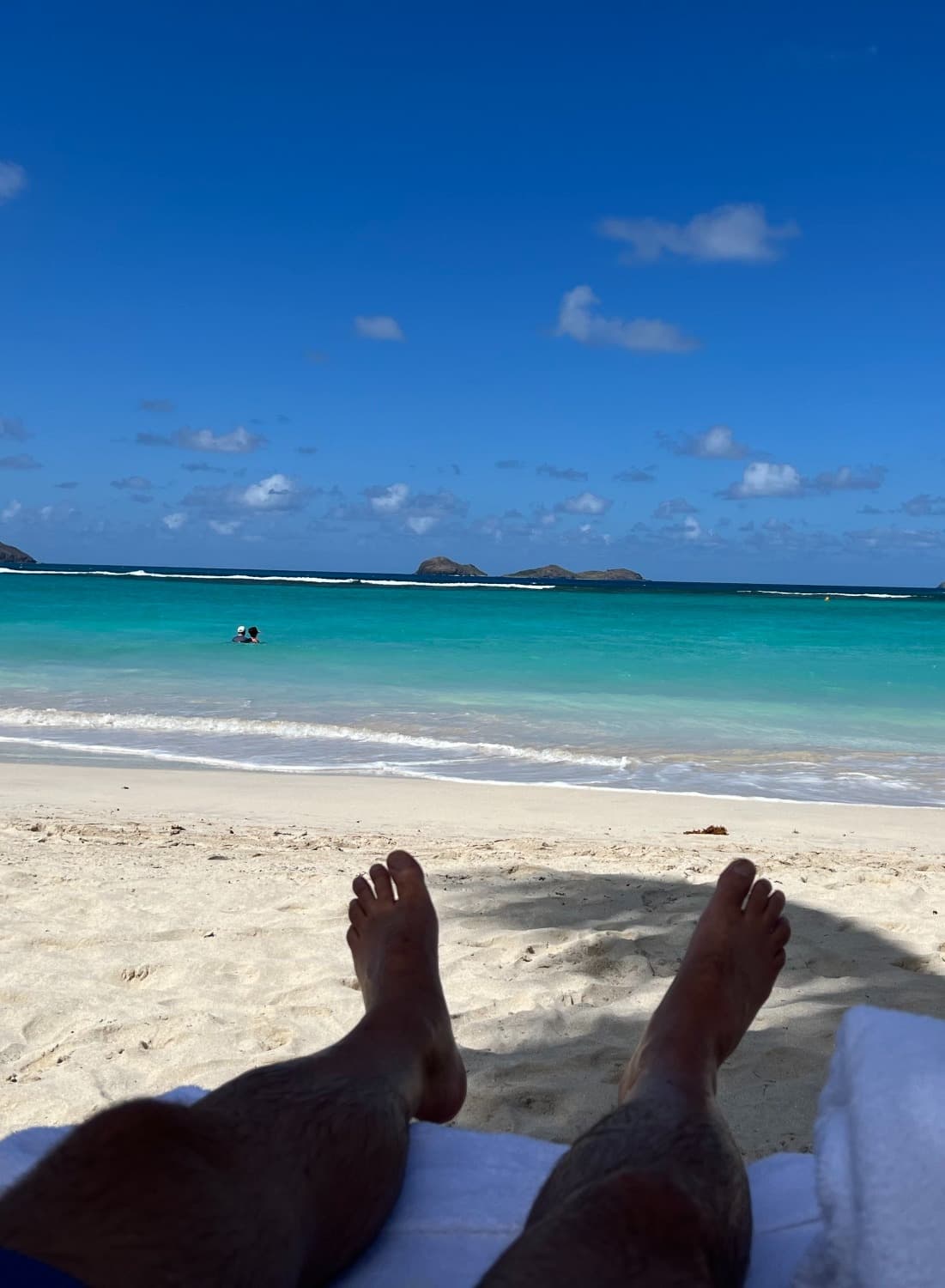 Advisor feet in a beach lounge chair with ocean and blue sky in the distance.