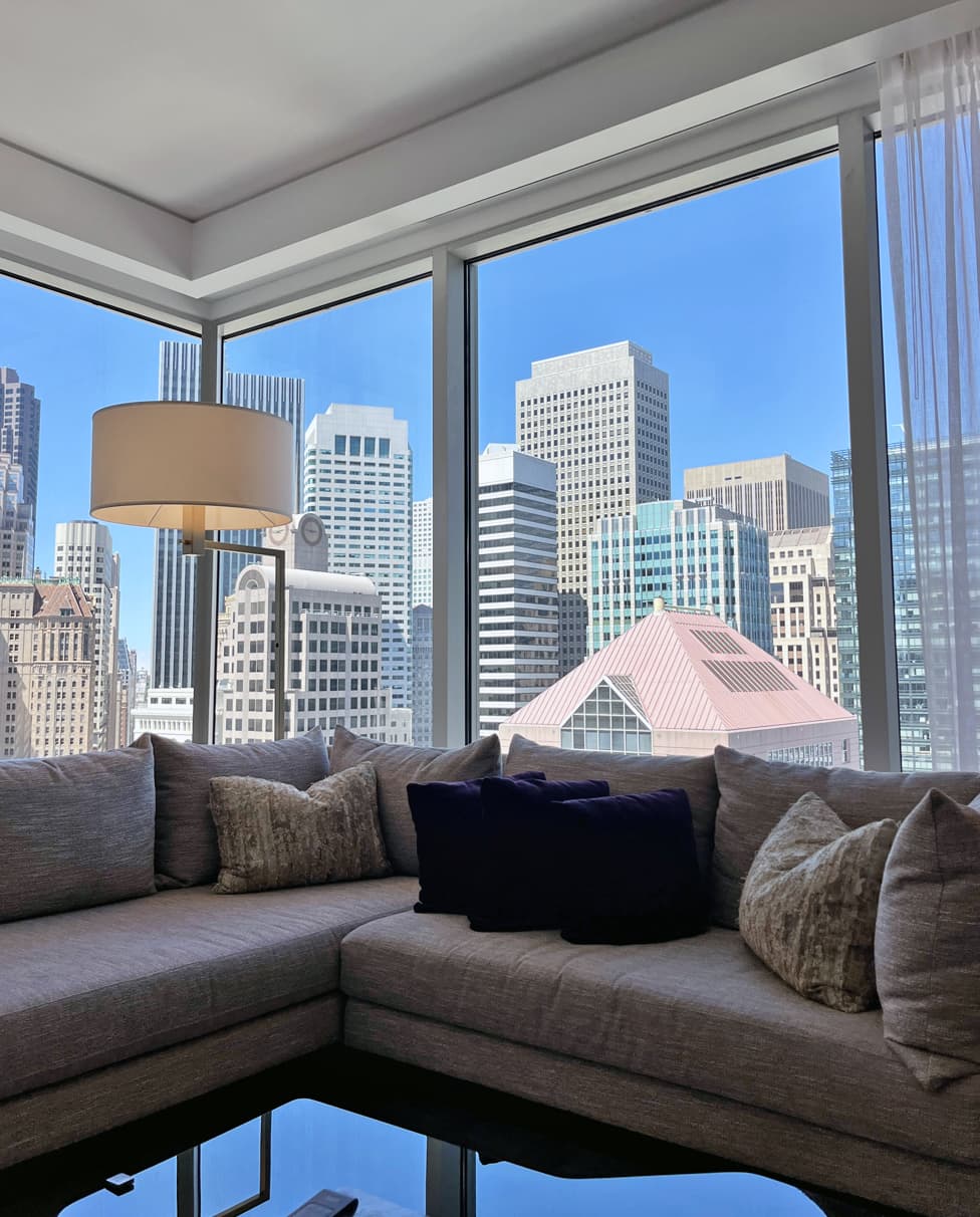 An indoor lounge area with large, floor-to-ceiling windows with a view of a city skyline