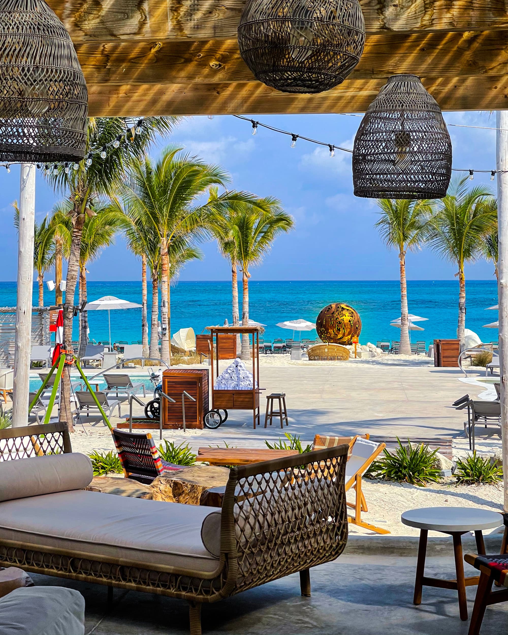A view of a luxe beach club with lounge seating and a white-sand beach.