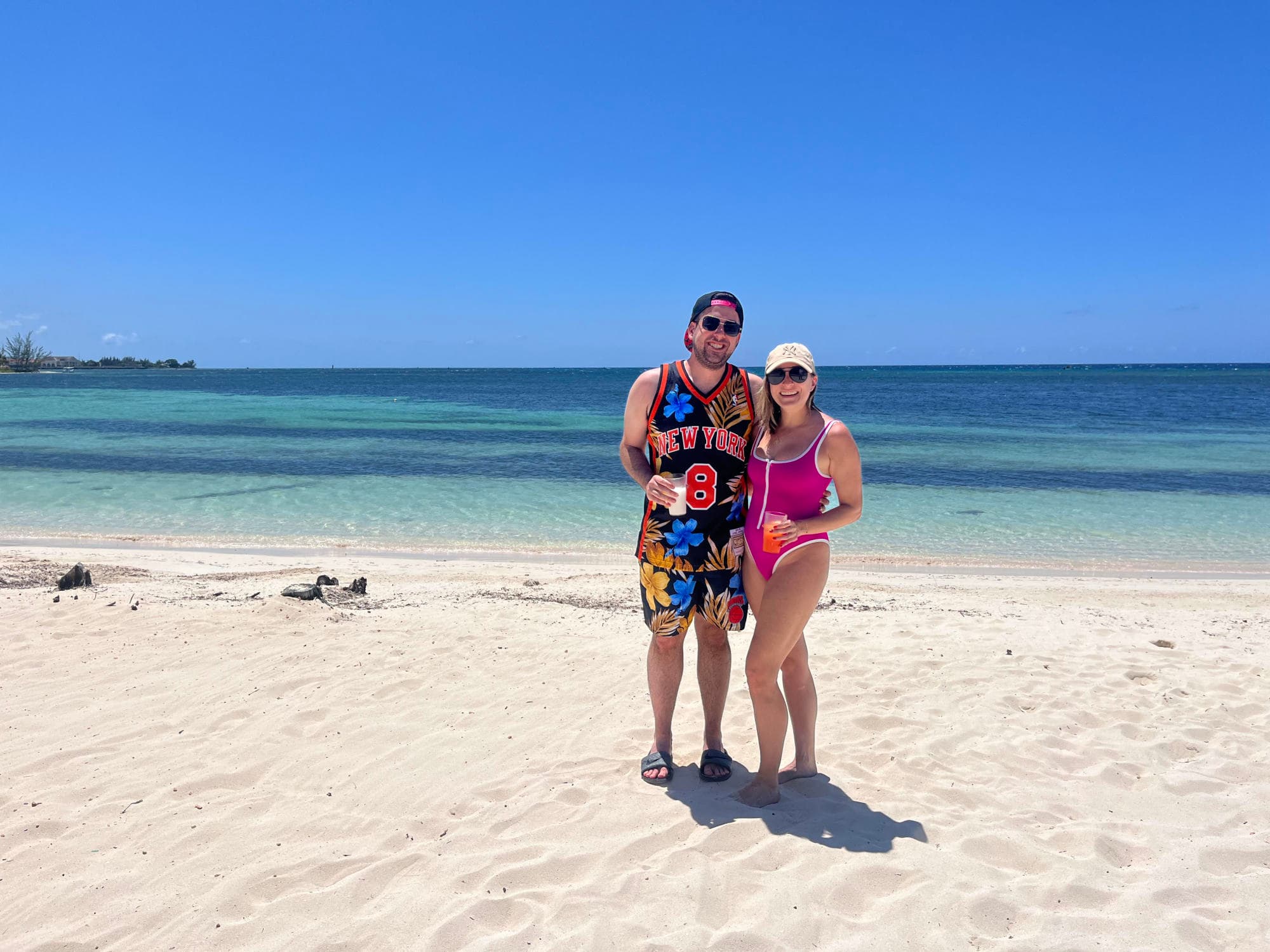 A picture of a couple posing on a beautiful beach with white sand and turquoise waters.