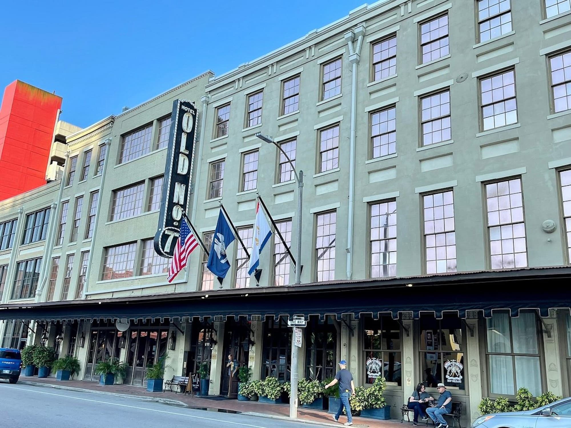 The green exterior of the Old No 77 Hotel in New Orleans with flags flying above the entrance