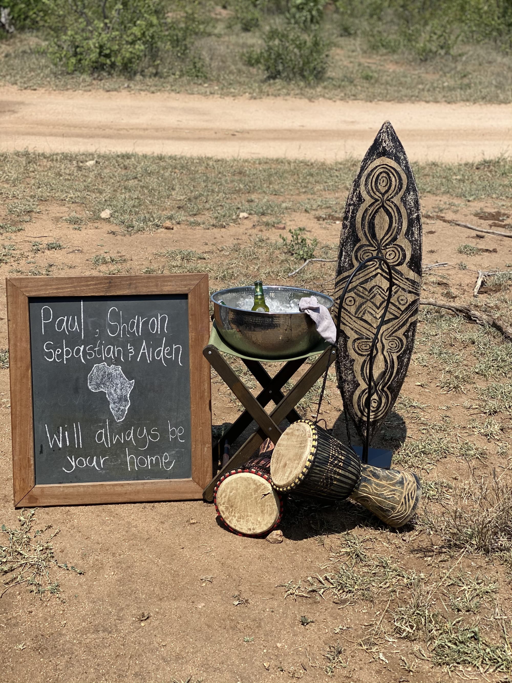 Welcome display with a welcome message on a board, a traditional surf board and drums and drinks in nature