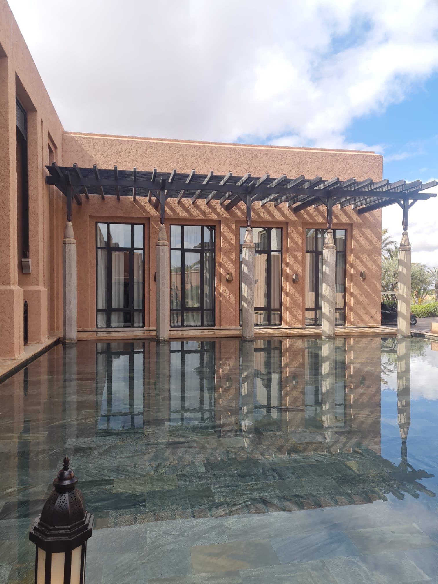 View of a hotel in Marrakech with water and orange-colored building