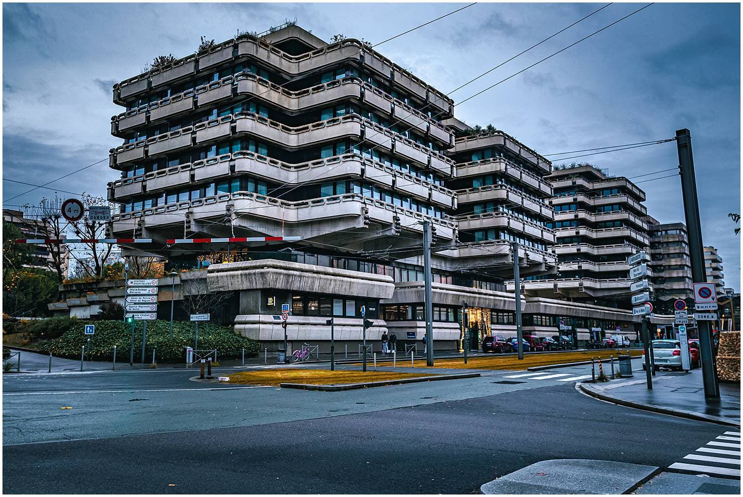 A view of a city street and building with multiple balconies and windows.