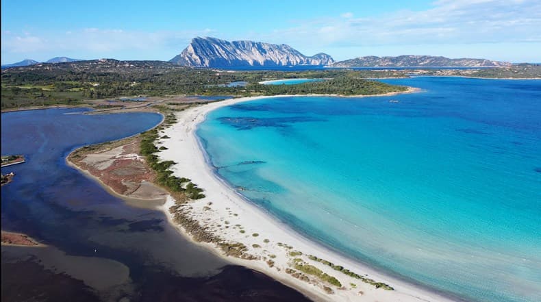 An aerial view of an inlet beach with mountains in the distance