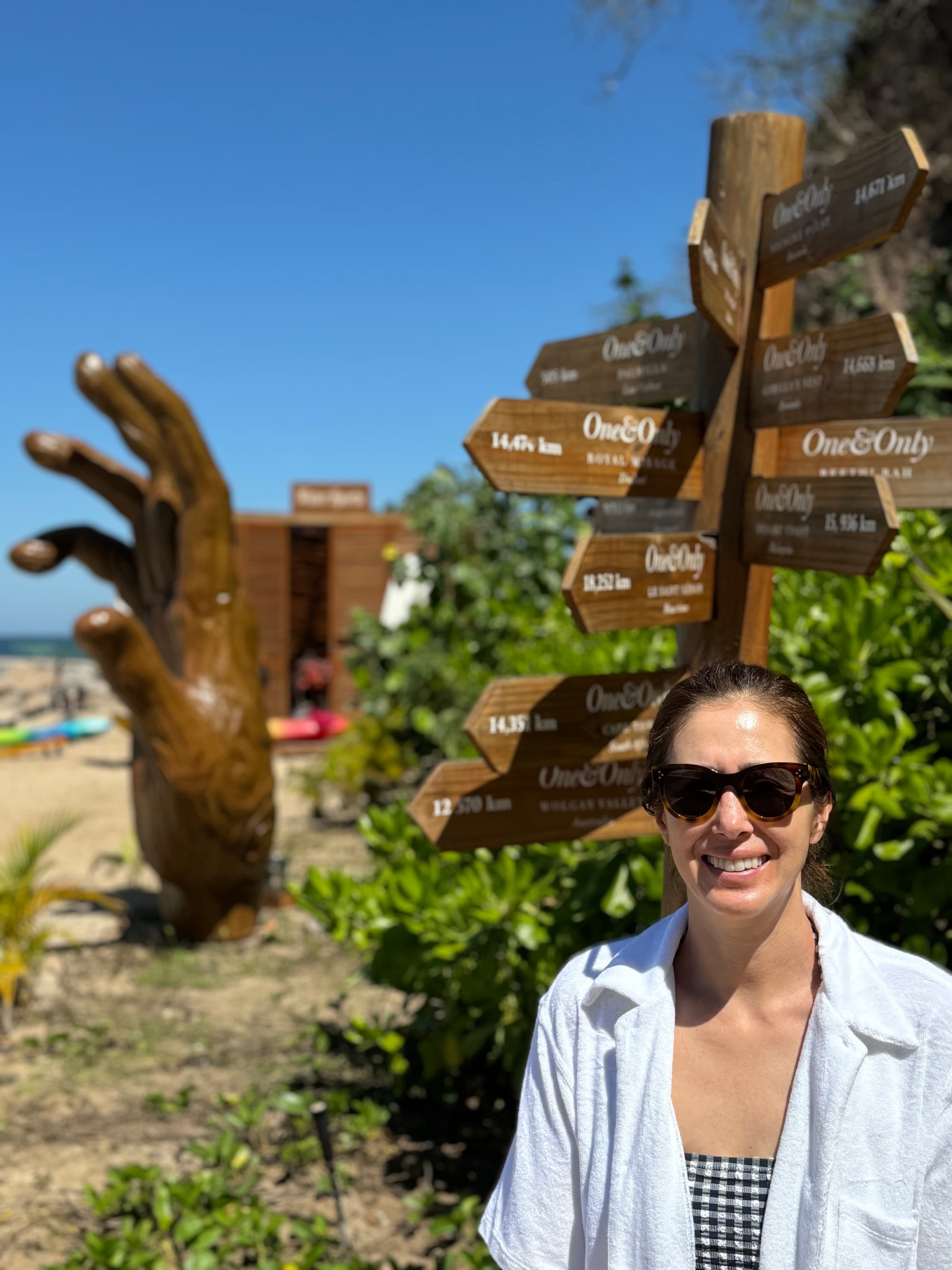 A person posing for a photo in front of a statue of a hand