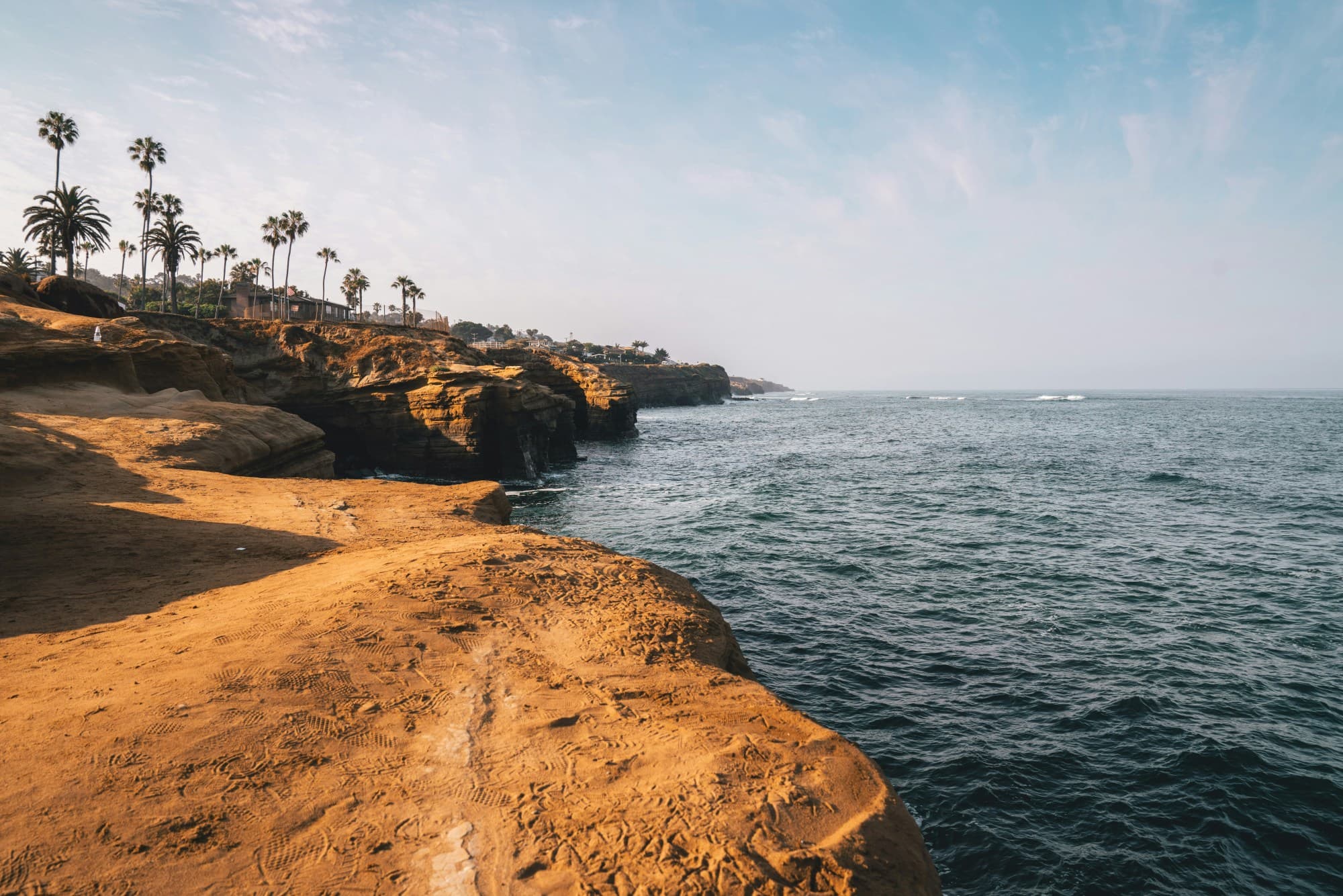Rocky cliffs, palm trees and the blue sea view.