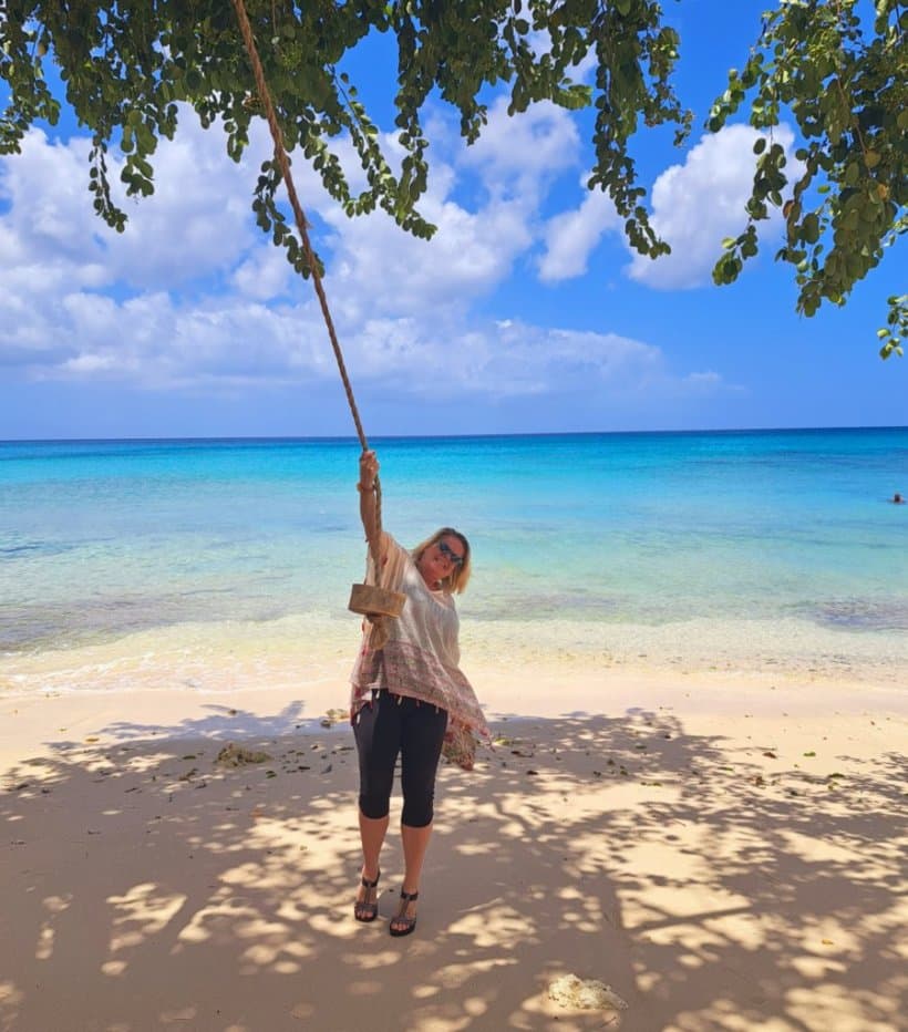 Travel advisor posing on the seaside with a rope swing.