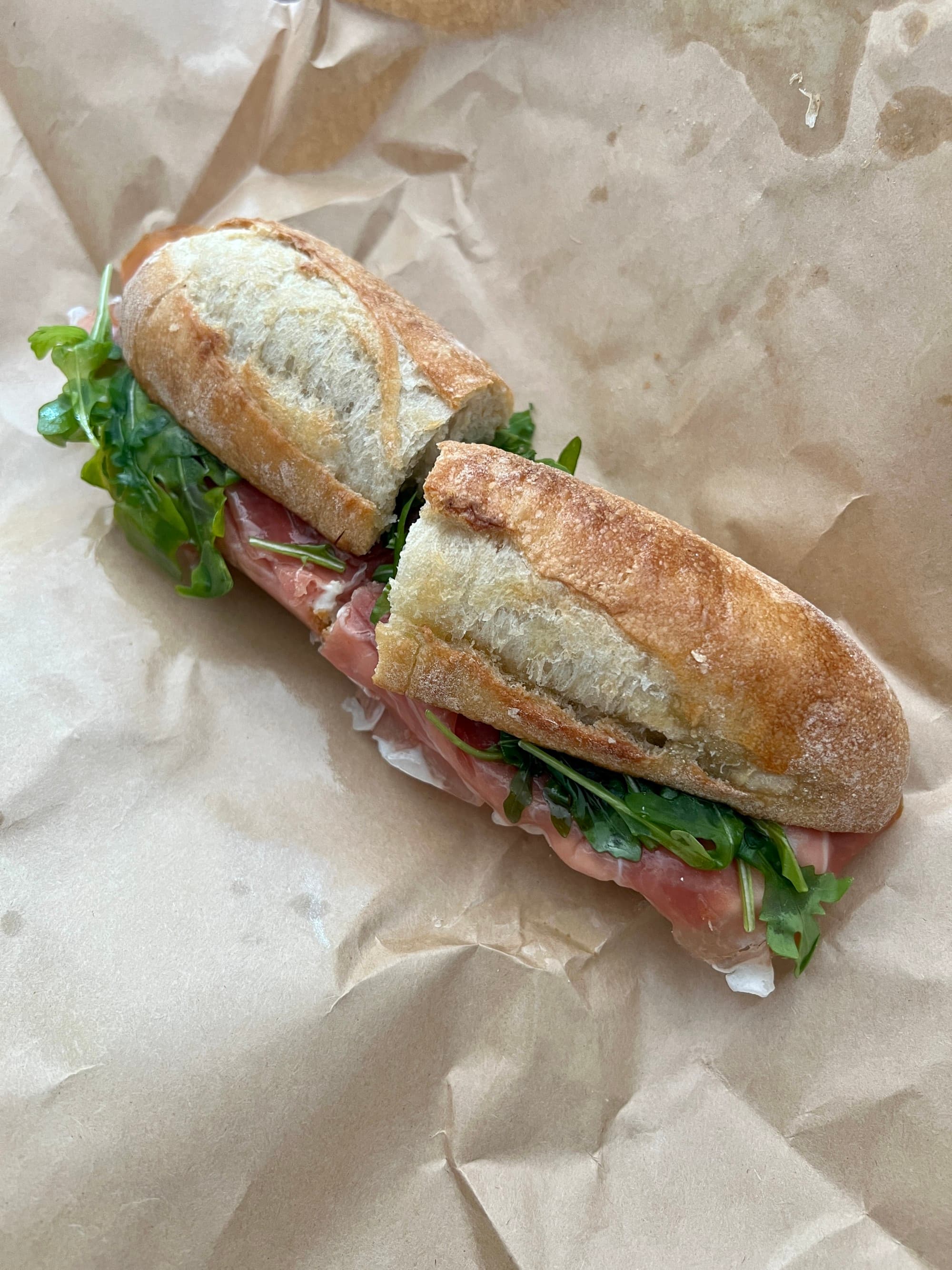 Long bun sandwich with meat and lettuce.