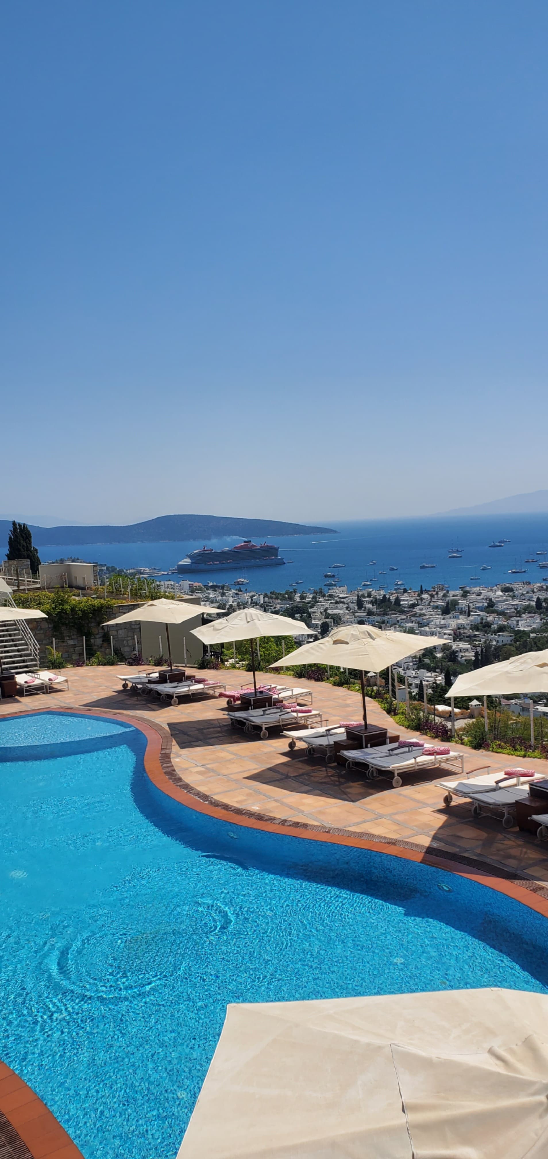 Loungers and umbrellas cluster around the pool's edge on a sunny day.