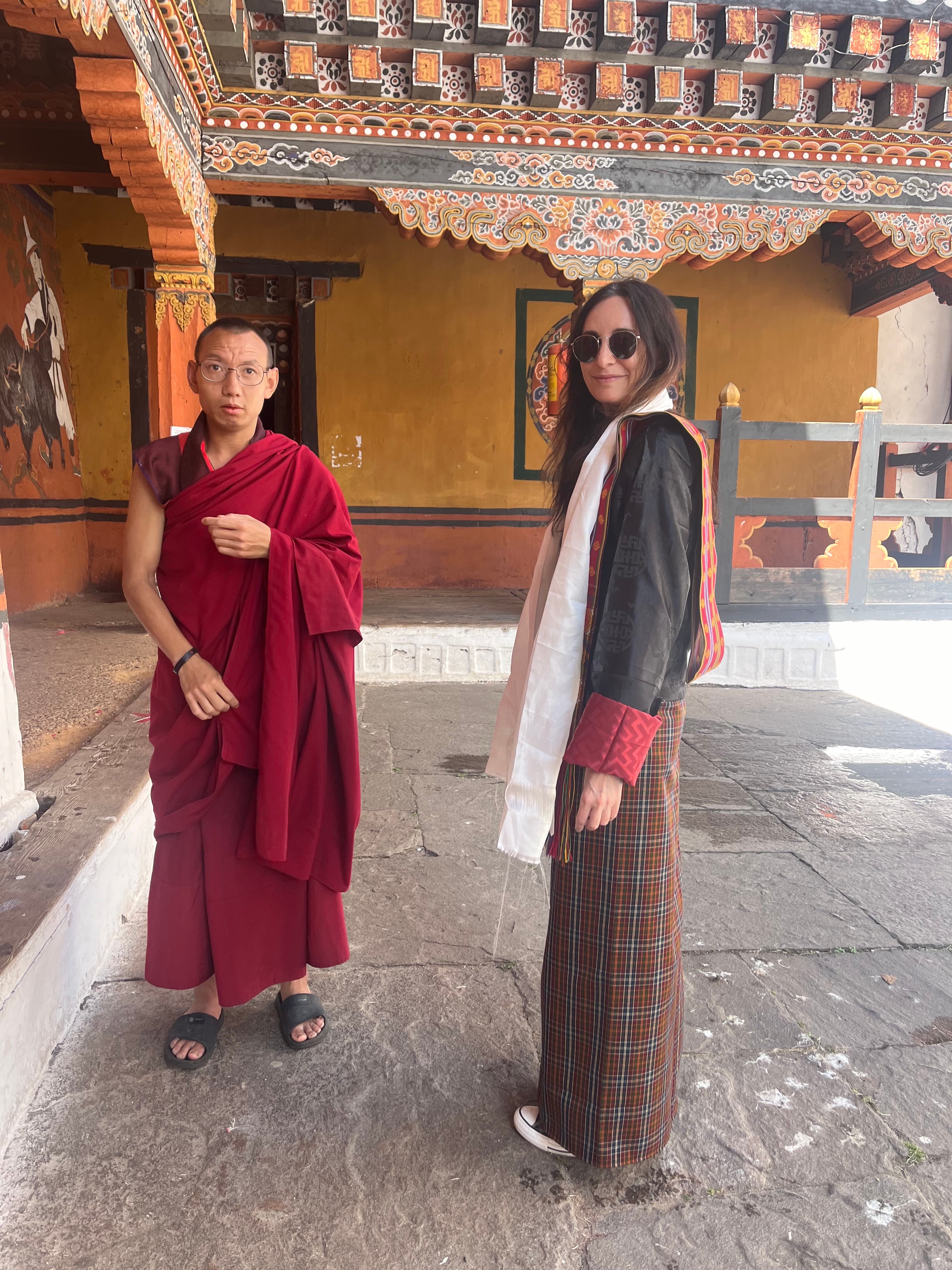 Travel advisor Karen standing next to a man in traditional red robe in the patio of an Asian-style temple.