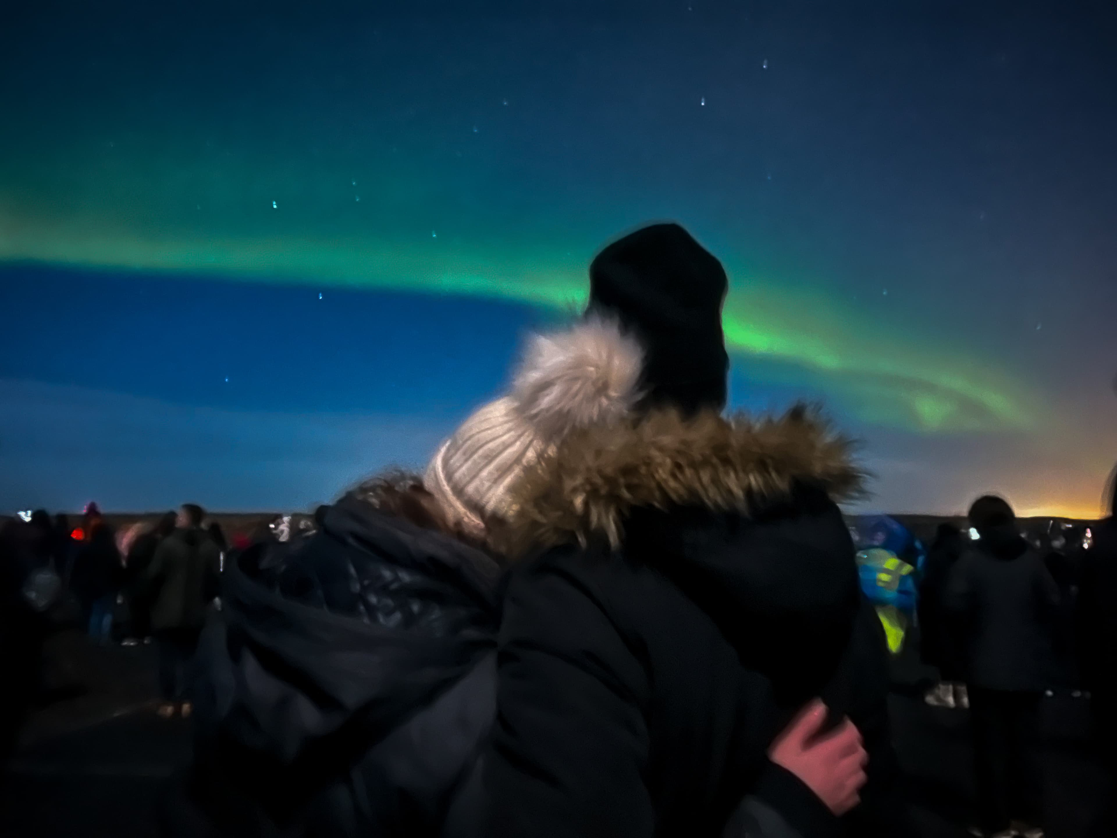 Ashley with her head on partners shoulder and both looking at the beautiful view of the Northern lights