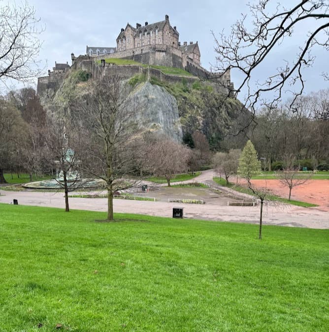 A view of a field and a castle at the top of a mountain