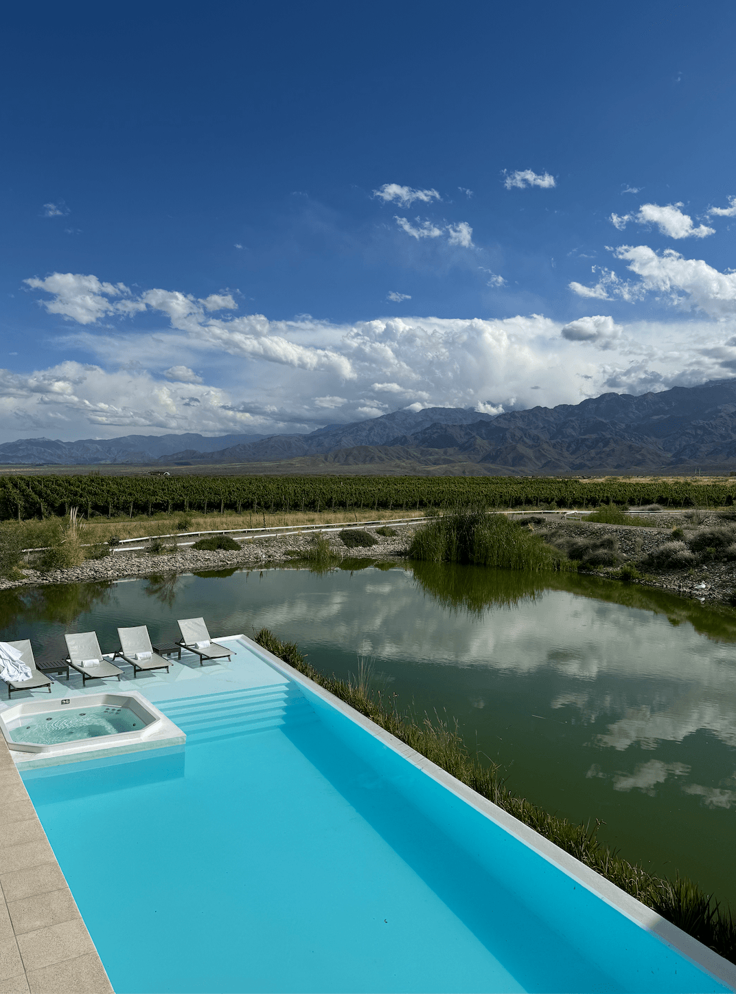 A swimming pool near a body of water with mountains in the background.