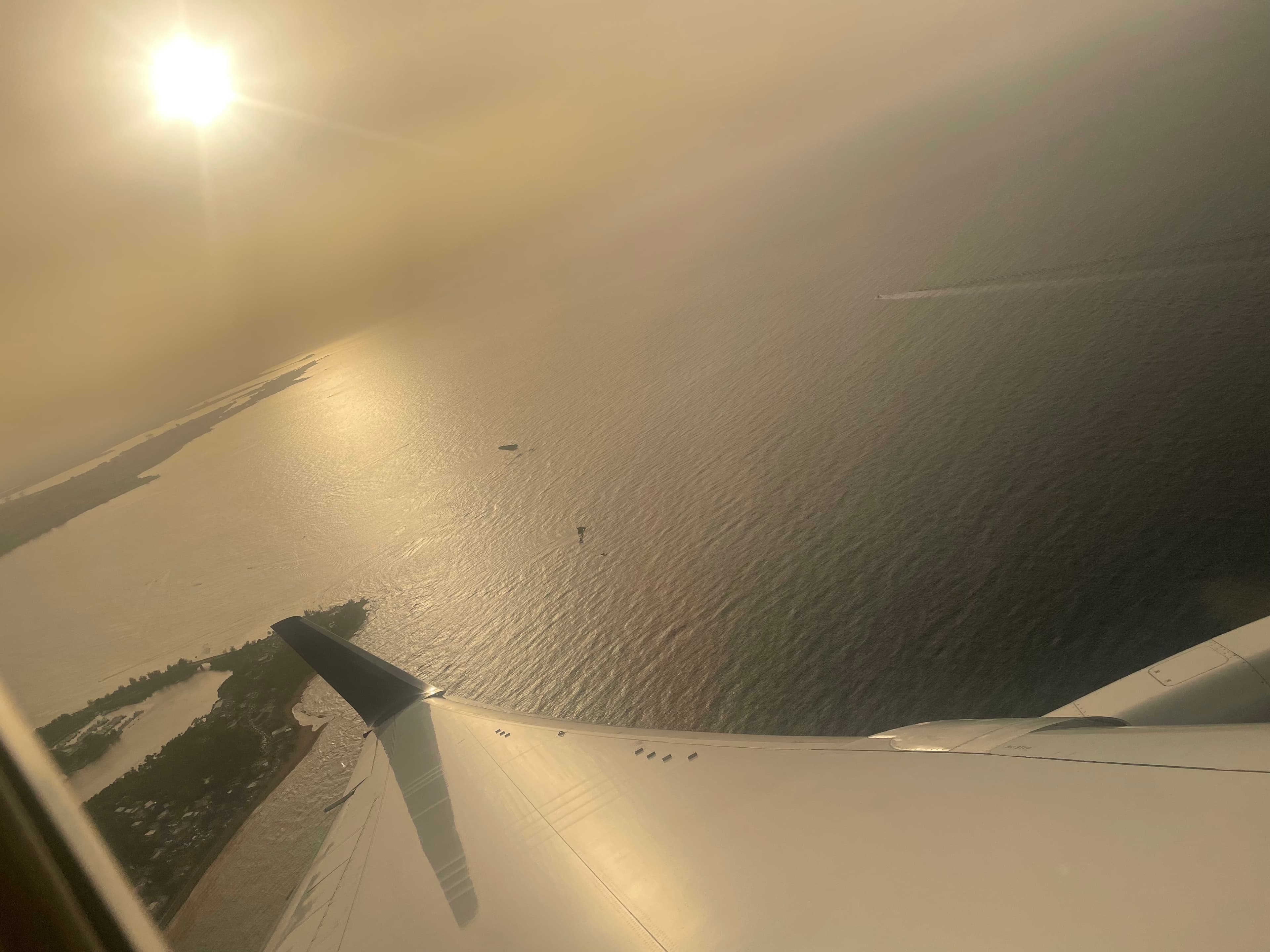 View from a plane of the ocean with the sun low in the sky