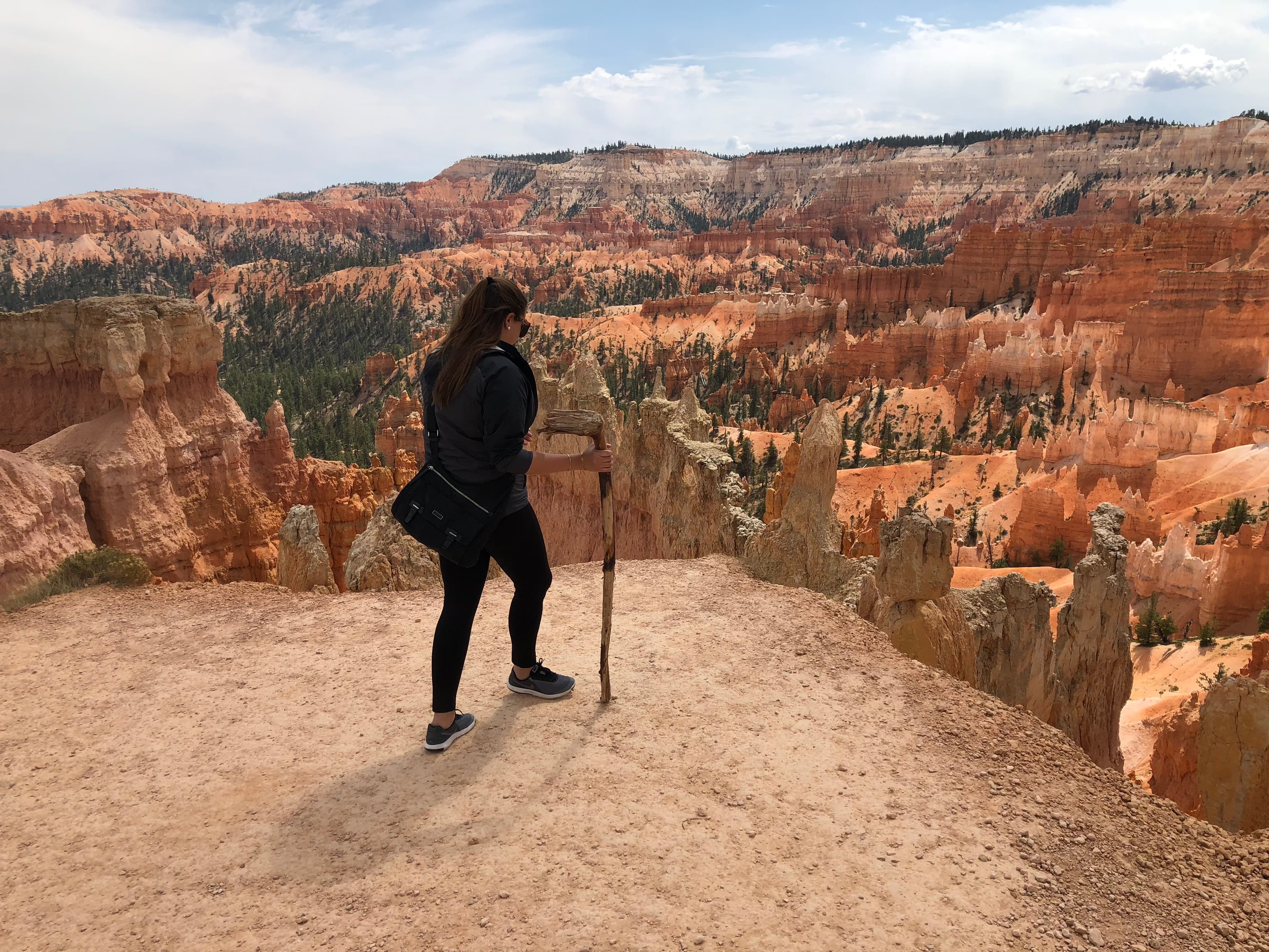 Travel advisor Andrea hiking Bryce Canyon National Park standing on a rock overlooking a beautiful canyon of orange-colored rock formations
