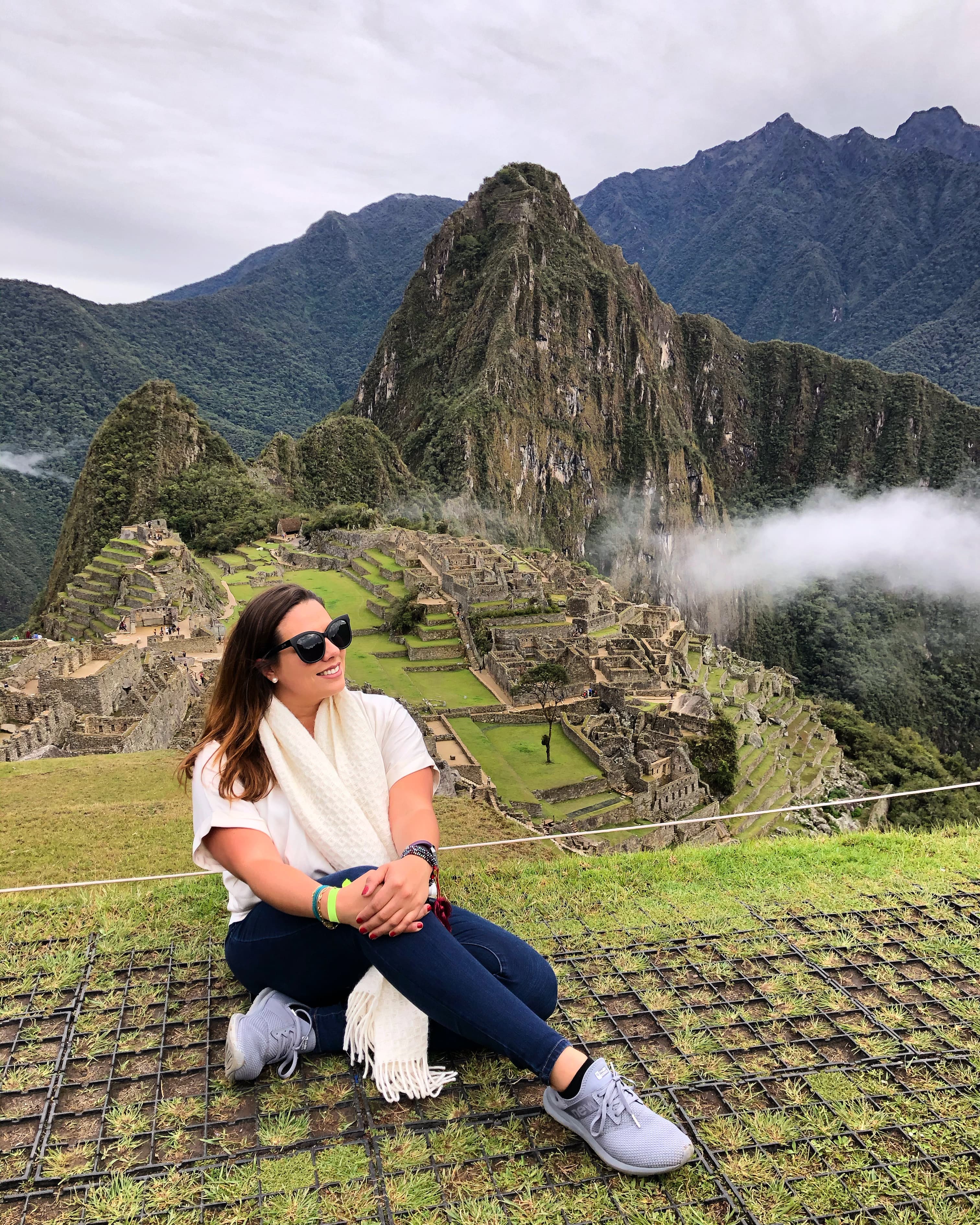 Travel advisor Andrea sitting on the ground in front of the historic Sanctuary of Machu Picchu