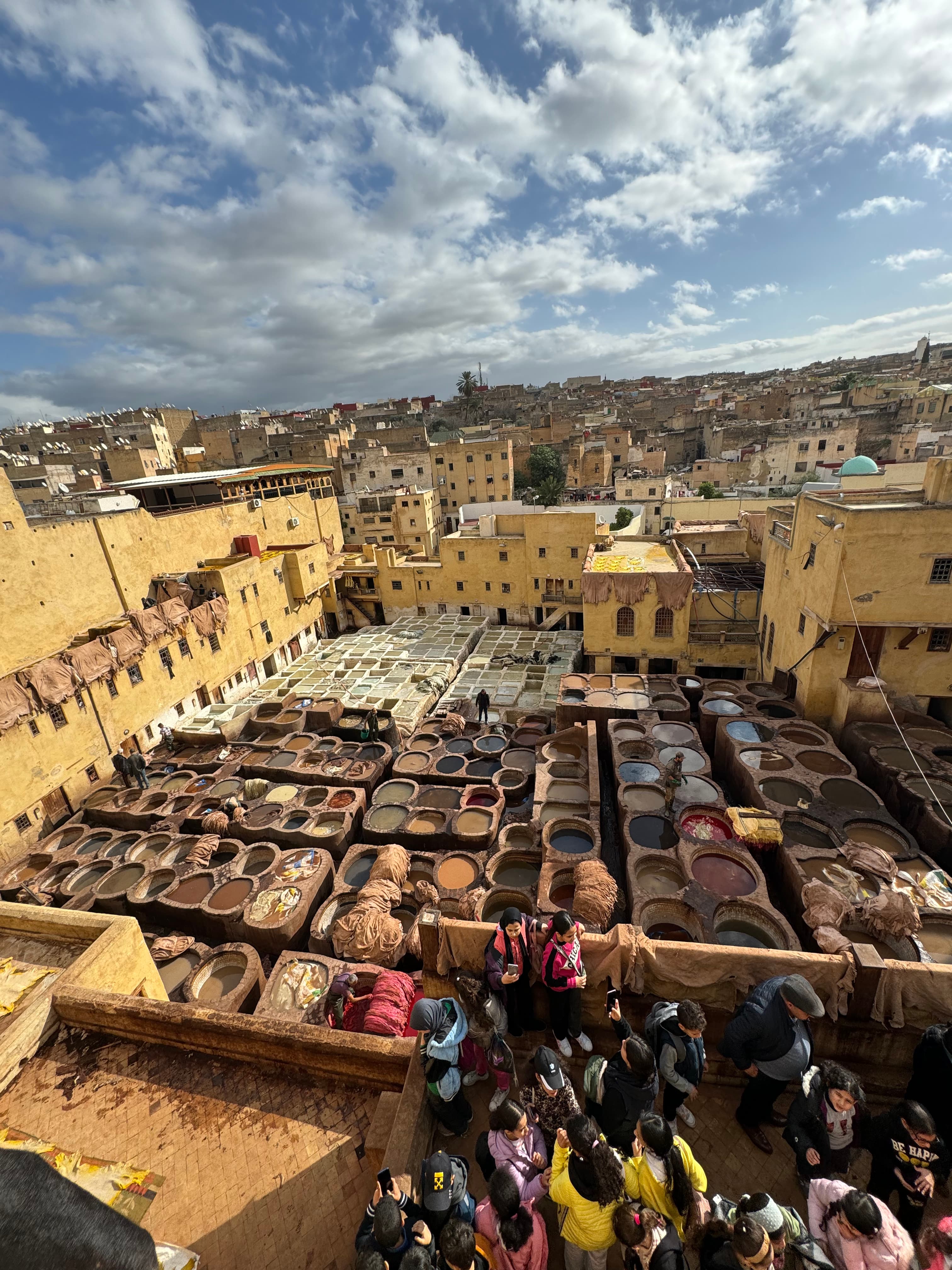 Aerial view of rooftop with many circular wells with different color liquids and people admiring the view