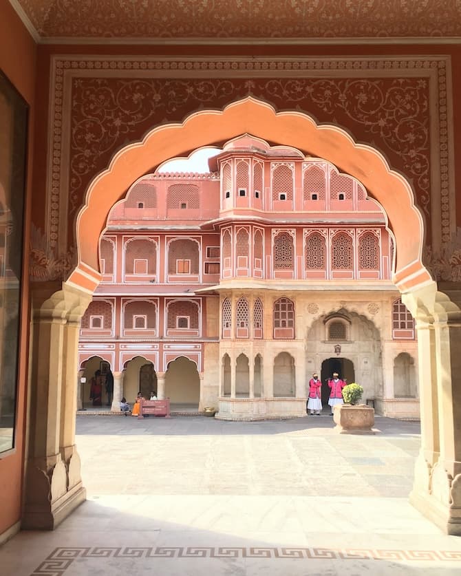 An archway with a view of a peach building in the distance