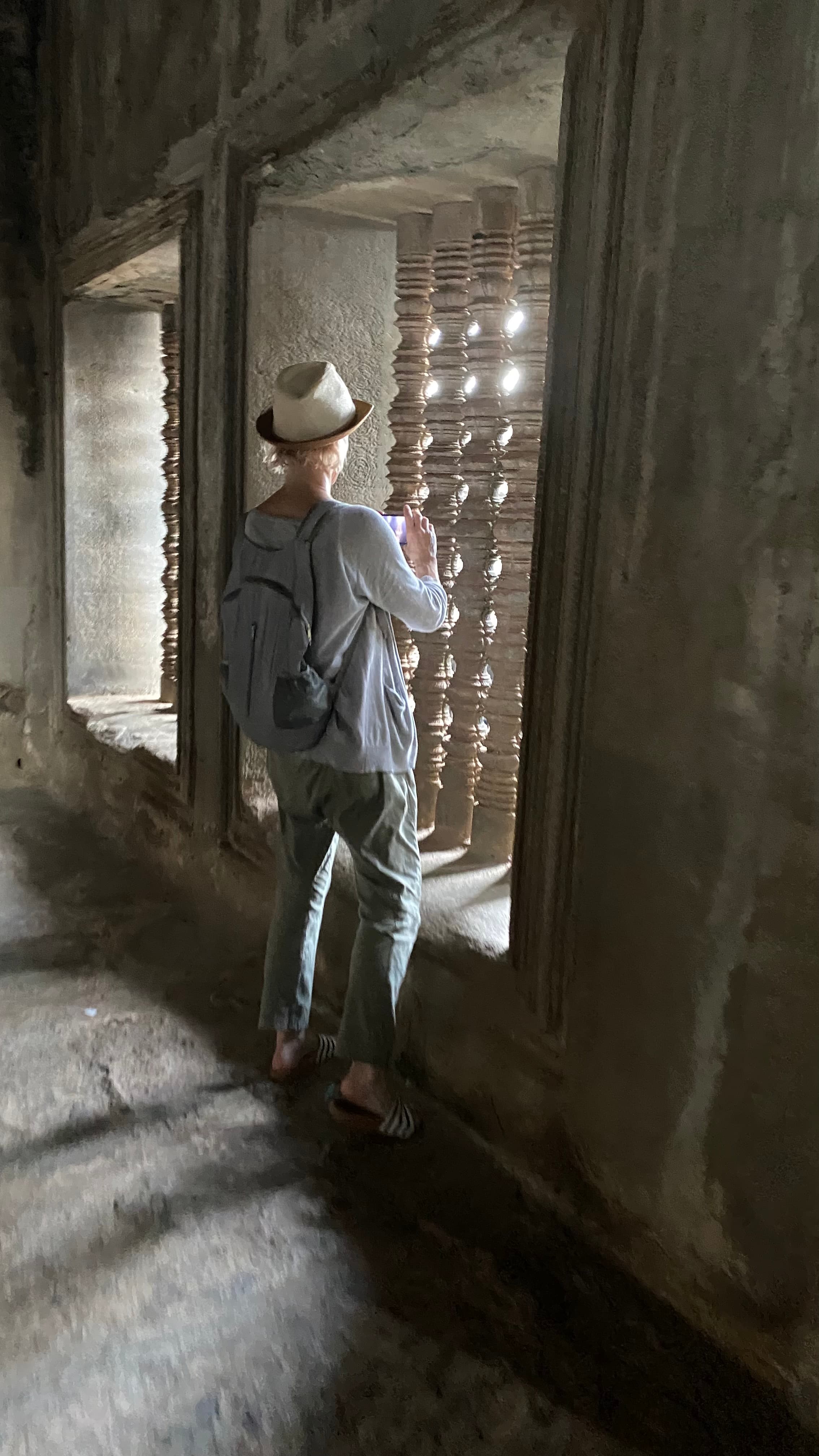 A person looking out of a window inside of a stone building.