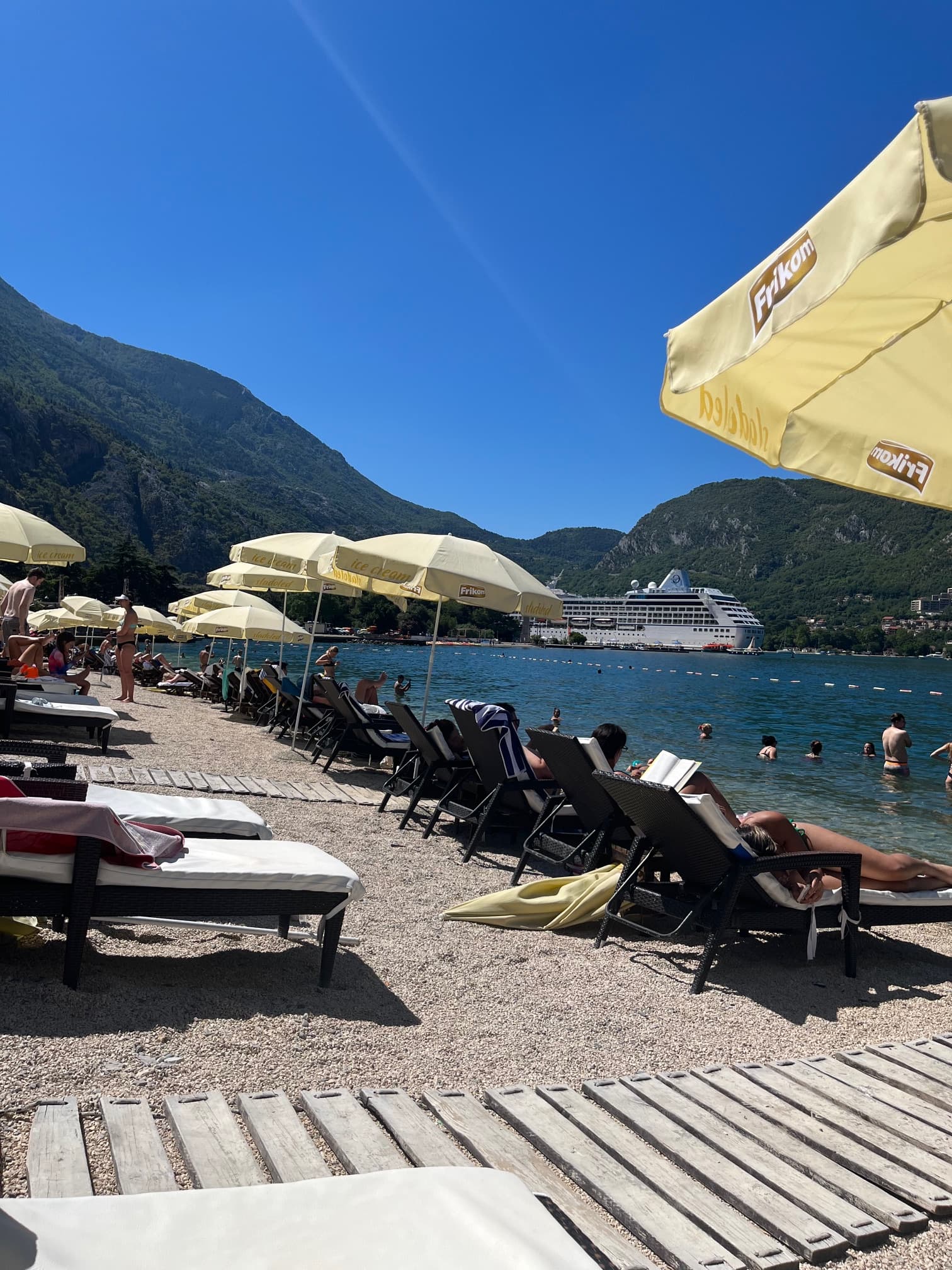 View of people lounging on the beach with yellow umbrellas and a cruise ship in view