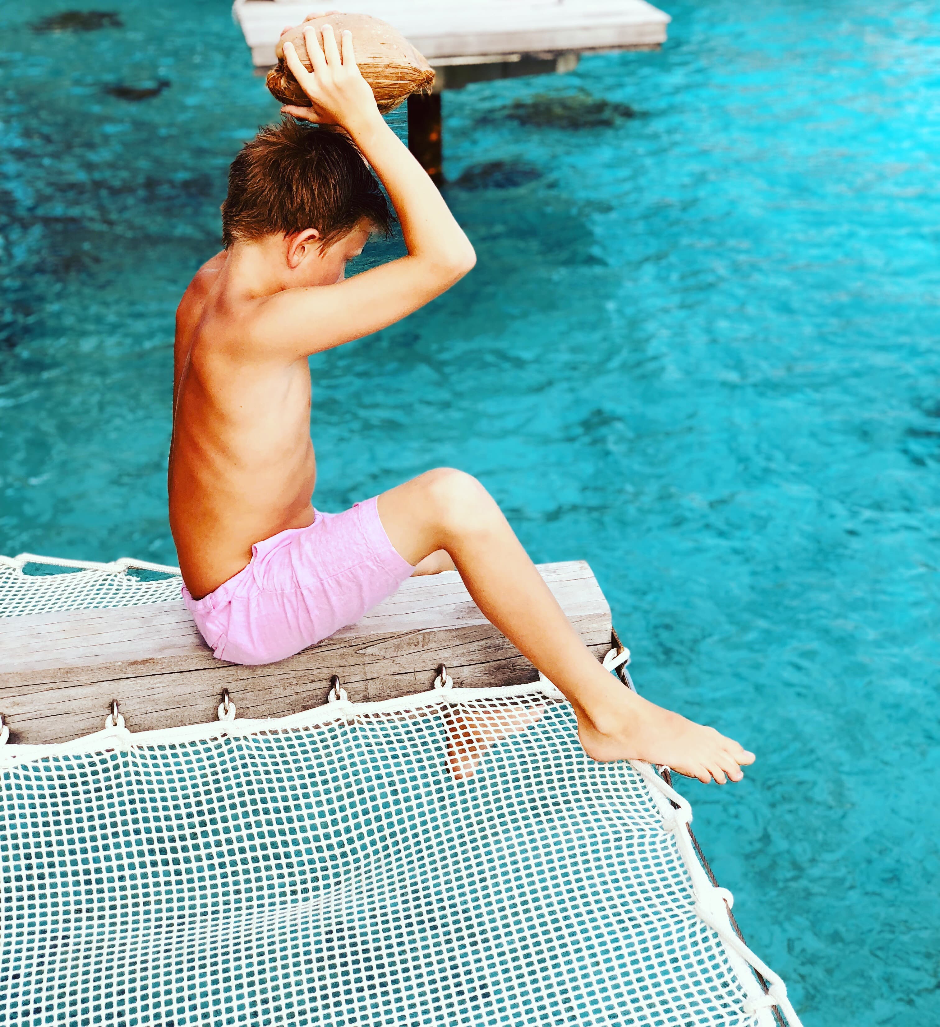 Kid holding a coconut in hand ready to throw in water