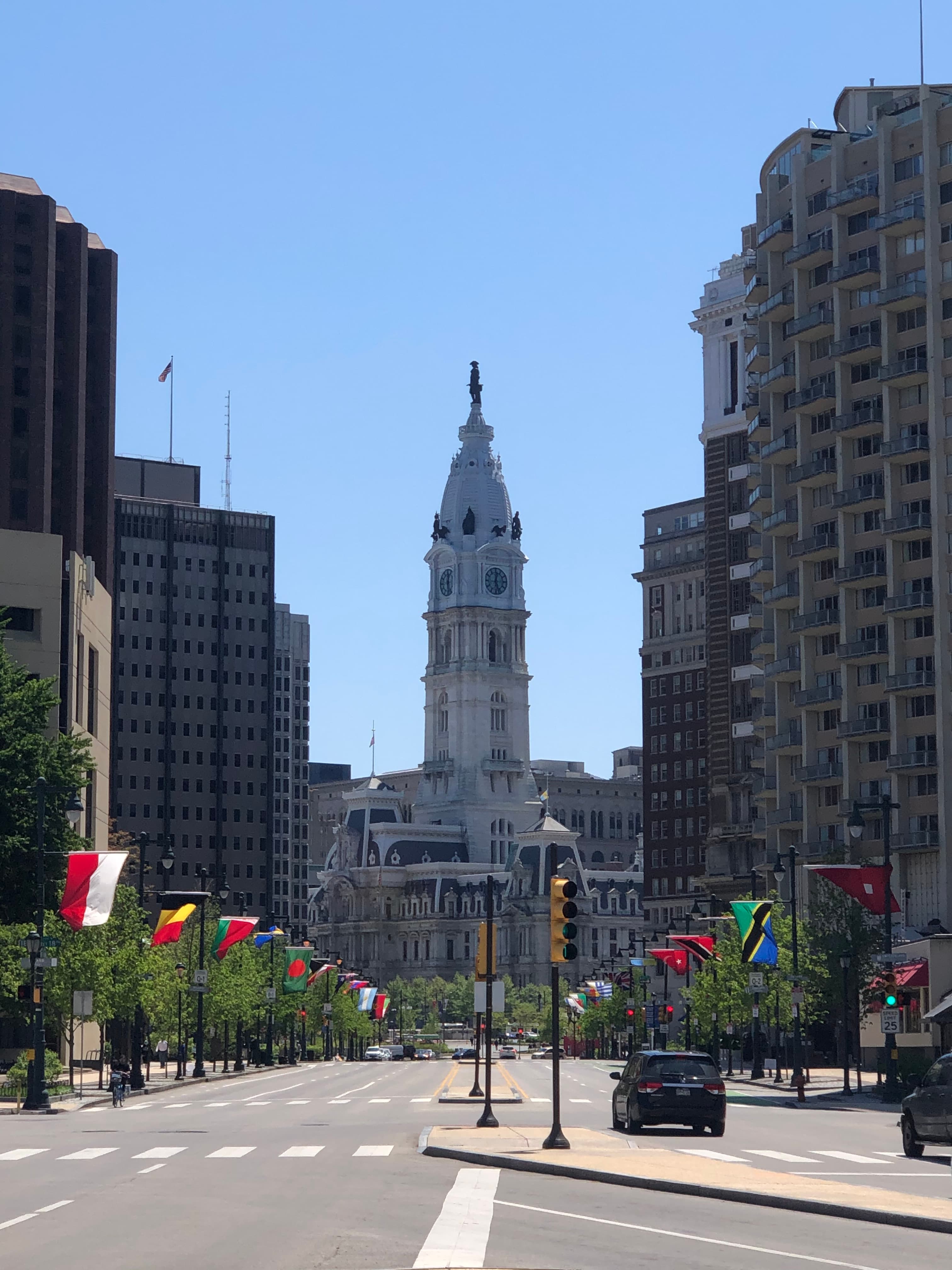 An view down an empty street with flags and a tall government building in the center.