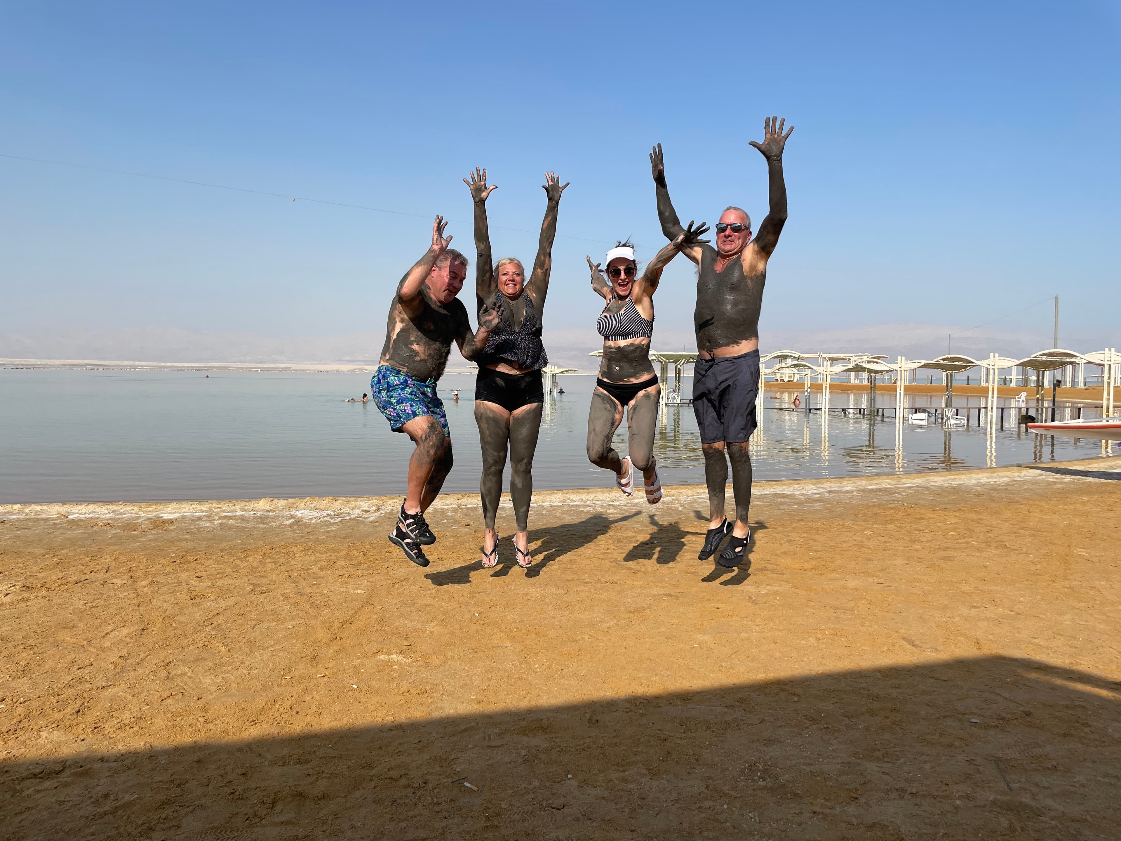 Travel advisor Leah Bedgood and three others jumping on a beach covered in mud