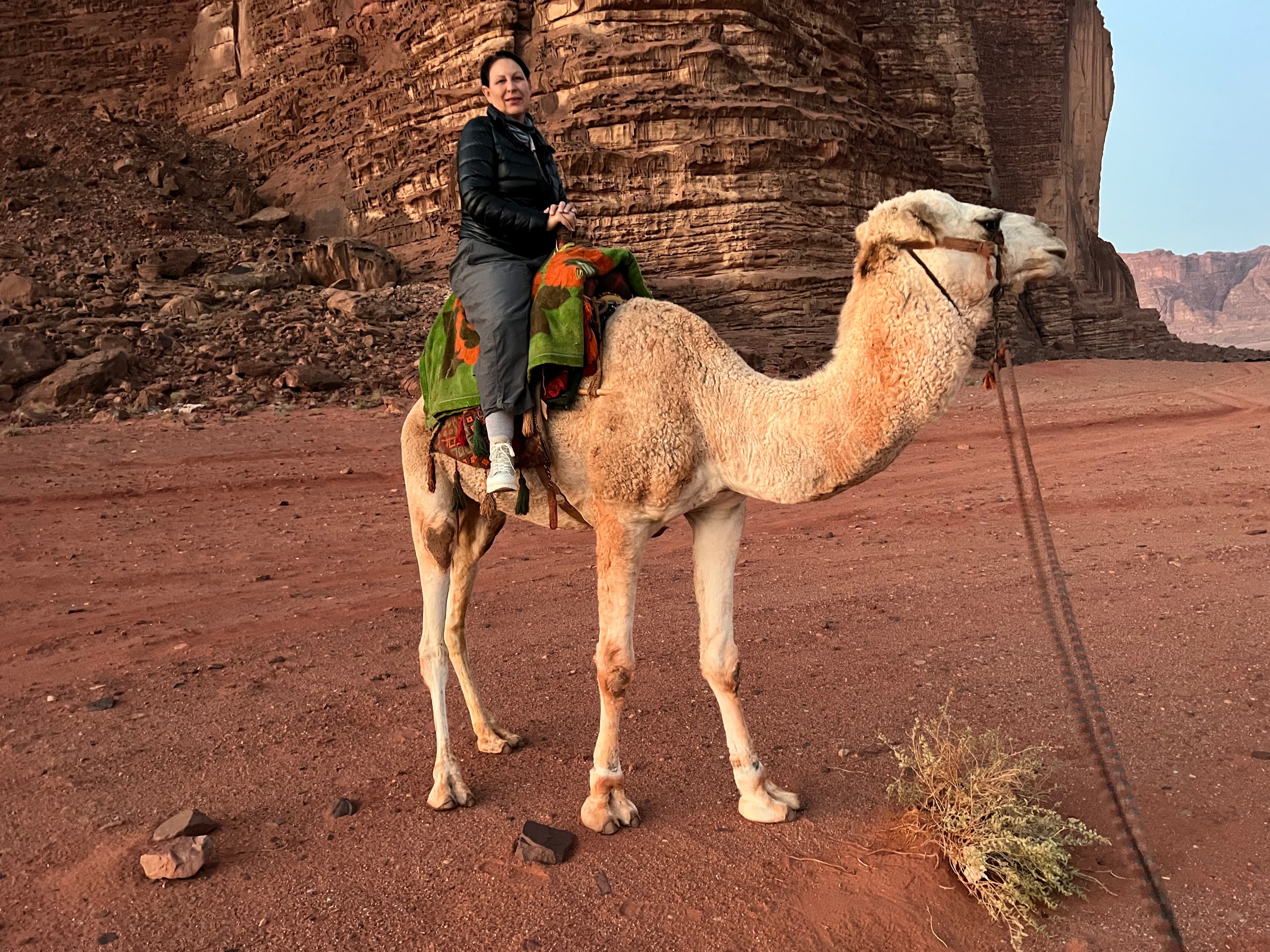 Travel advisor Suzanne riding camel on red-colored landscape