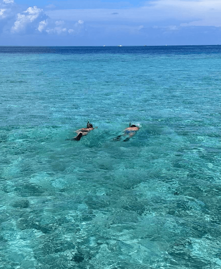 Two people floating in the turquoise blue water.